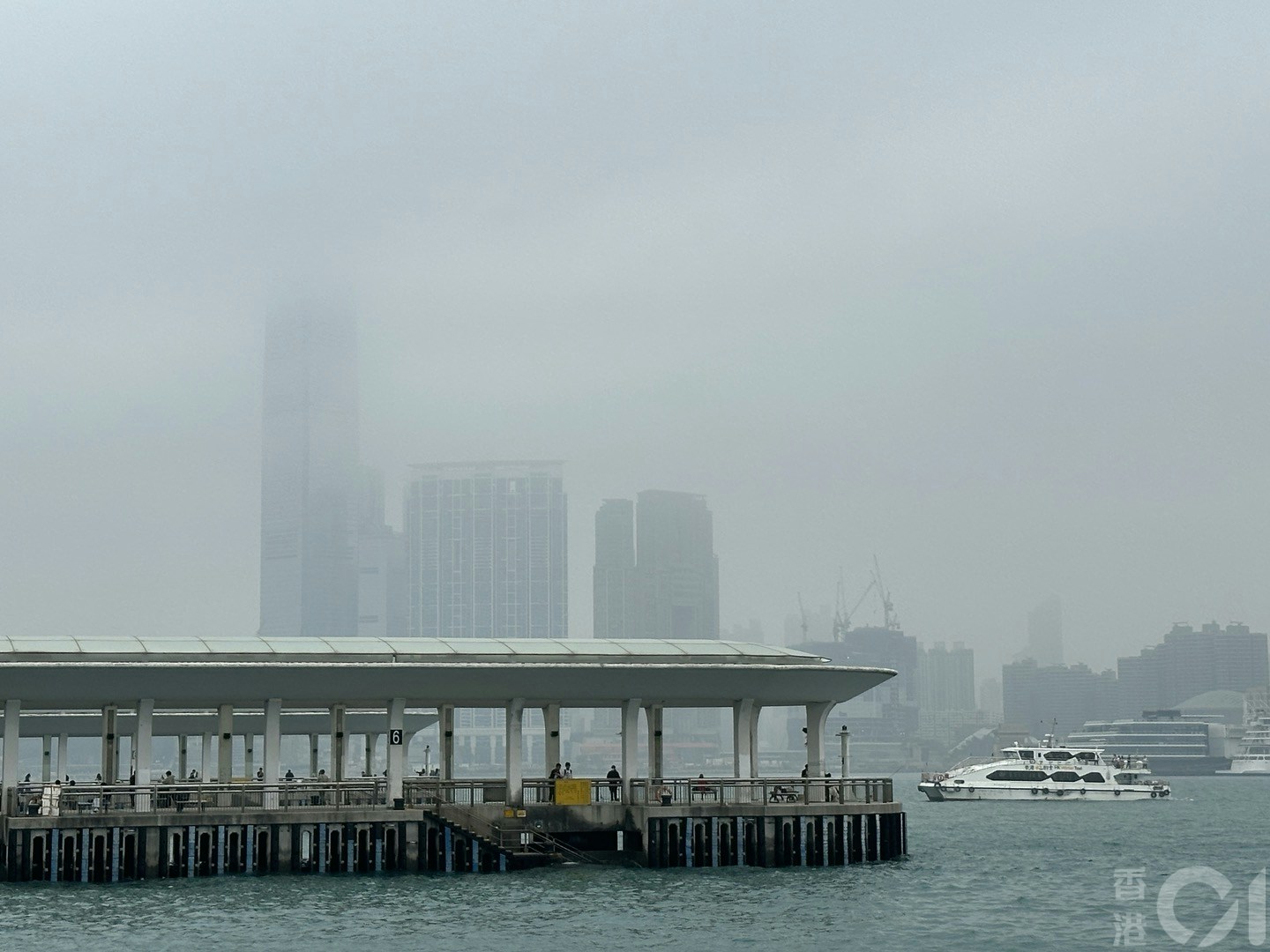 3月16日潮湿有雾，维港一片灰蒙蒙，在中环海滨望向对岸，可见部份大厦高层被云雾遮蔽。（倪清江摄）