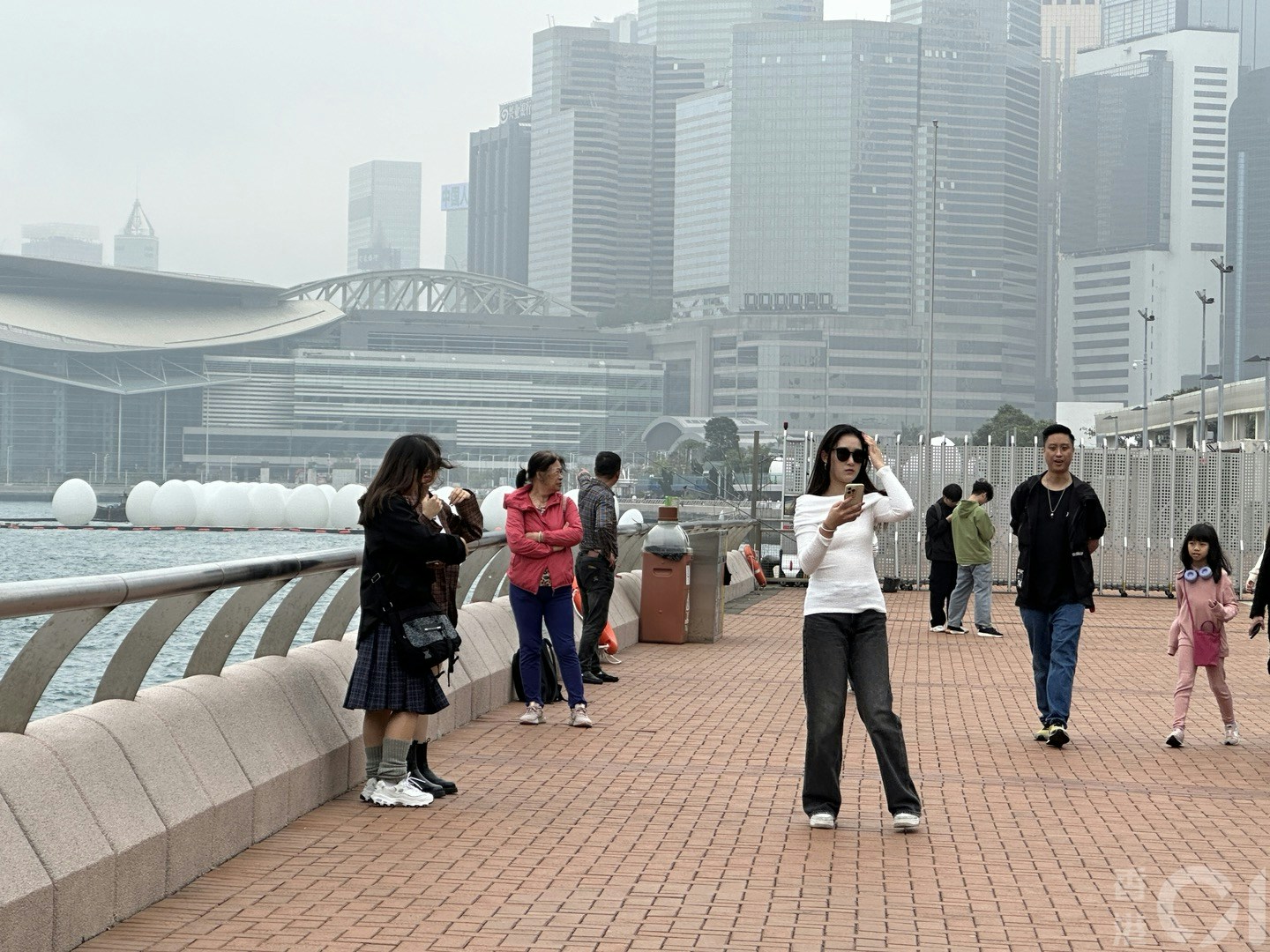 3月16日潮湿有雾，维港一片灰蒙蒙，在中环海滨有旅客照样打卡。（倪清江摄）