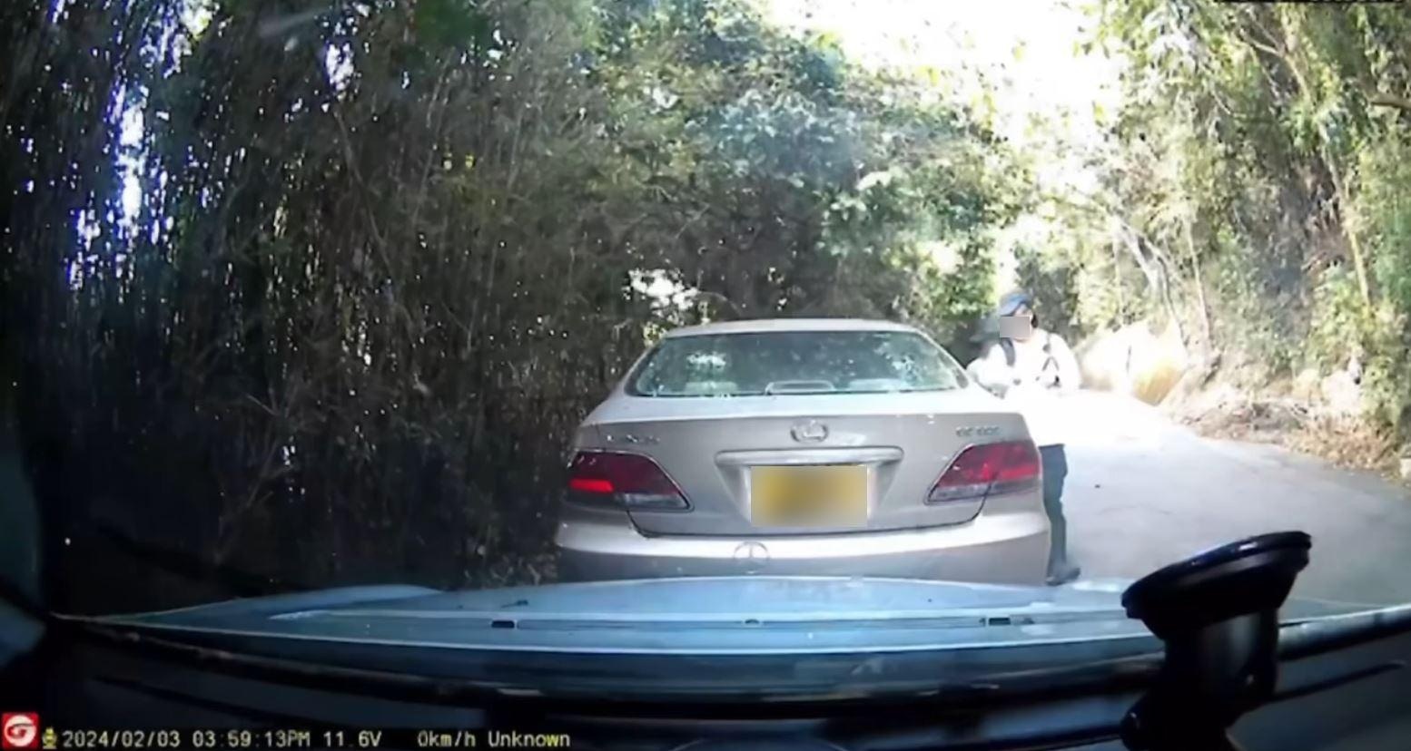 在10秒長的車Cam片中，1對身穿行山裝束的途人在郊外路上行走，其中走在前方的行山客疑逐一細看停泊路邊的車輛。（facebook影片截圖）