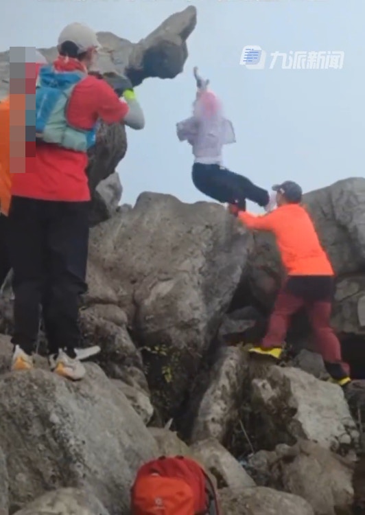 一名游客在龟仙石打卡拍照时双脚腾空，仅用双手攀住石头，落地时不慎跌倒。（九派新闻）