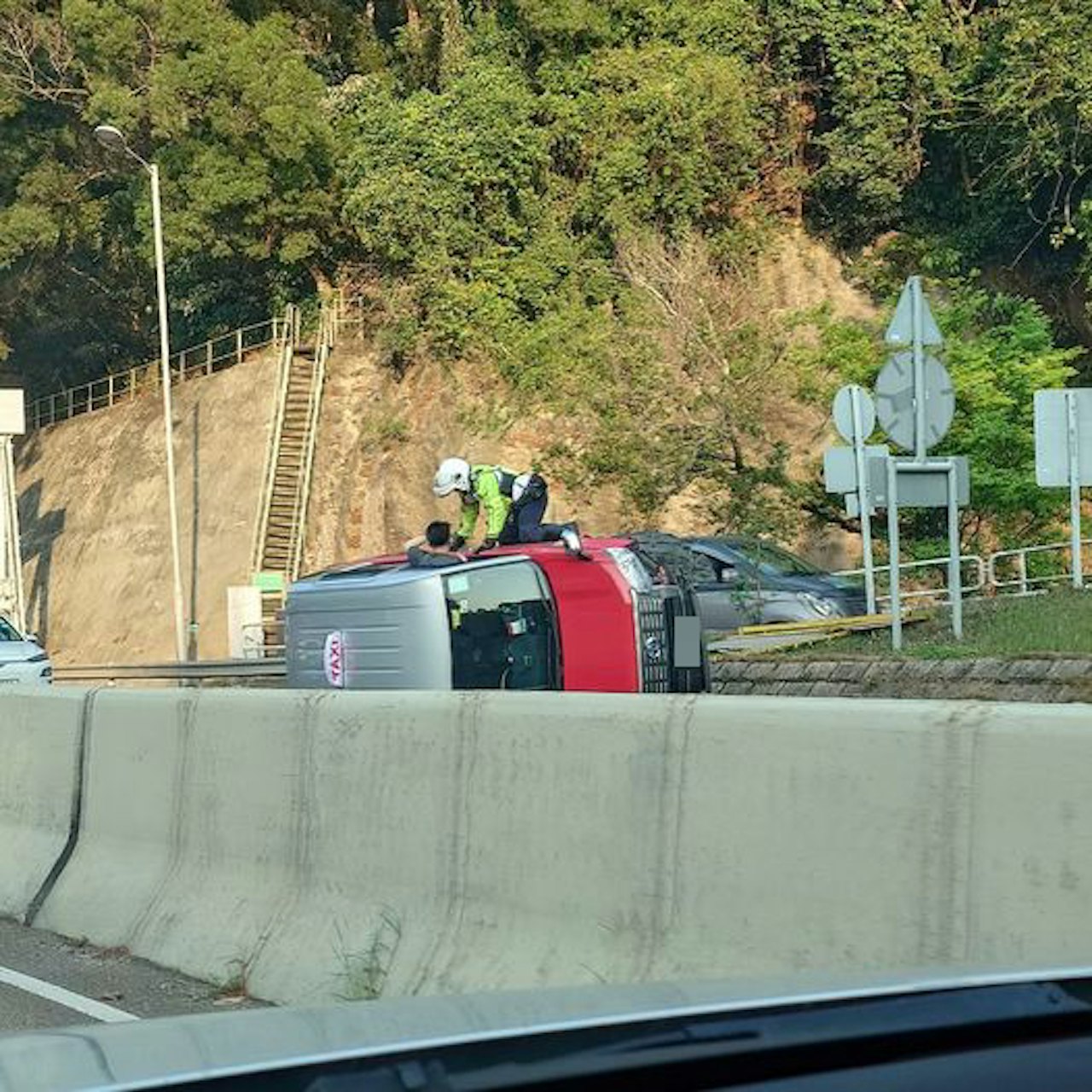 的士撞壆翻側,警員爬上車身協助車內的人離開車廂。(馬路的事 (即時交通資訊台)/Michael MC Cheung) 的士撞壆翻側,警員爬上車身協助車內的人離開車廂。(馬路的事 (即時交通資訊台)/Michael MC Cheung)