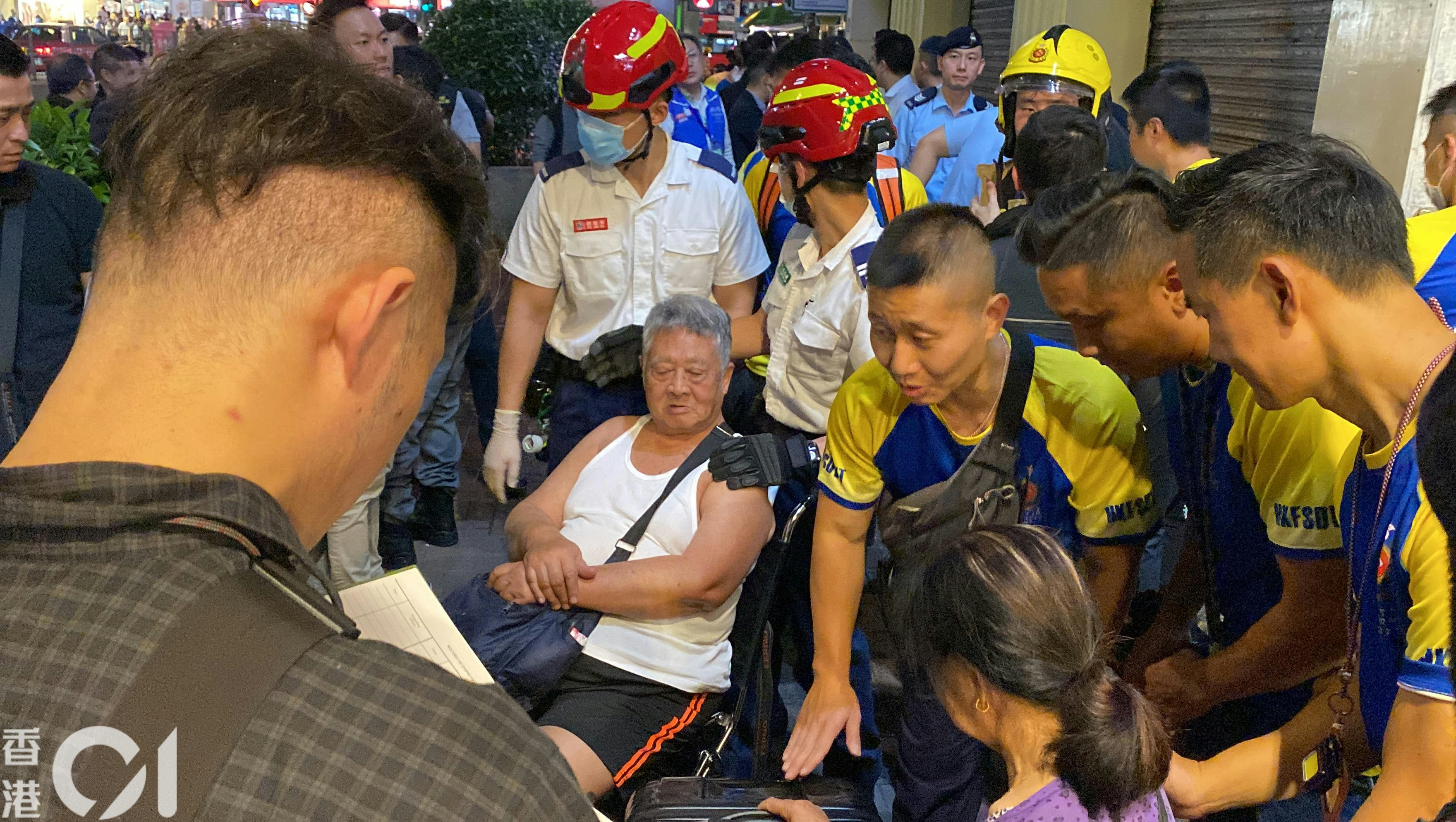 佐敦华丰大厦4月10日发生3级火，造成5死40人伤。香港消防处义工队成员（蓝黄上衣者）晚上在大厦「洗楼」，破门救出一名全日未有进食的老翁（白背心者）。（罗日升摄）