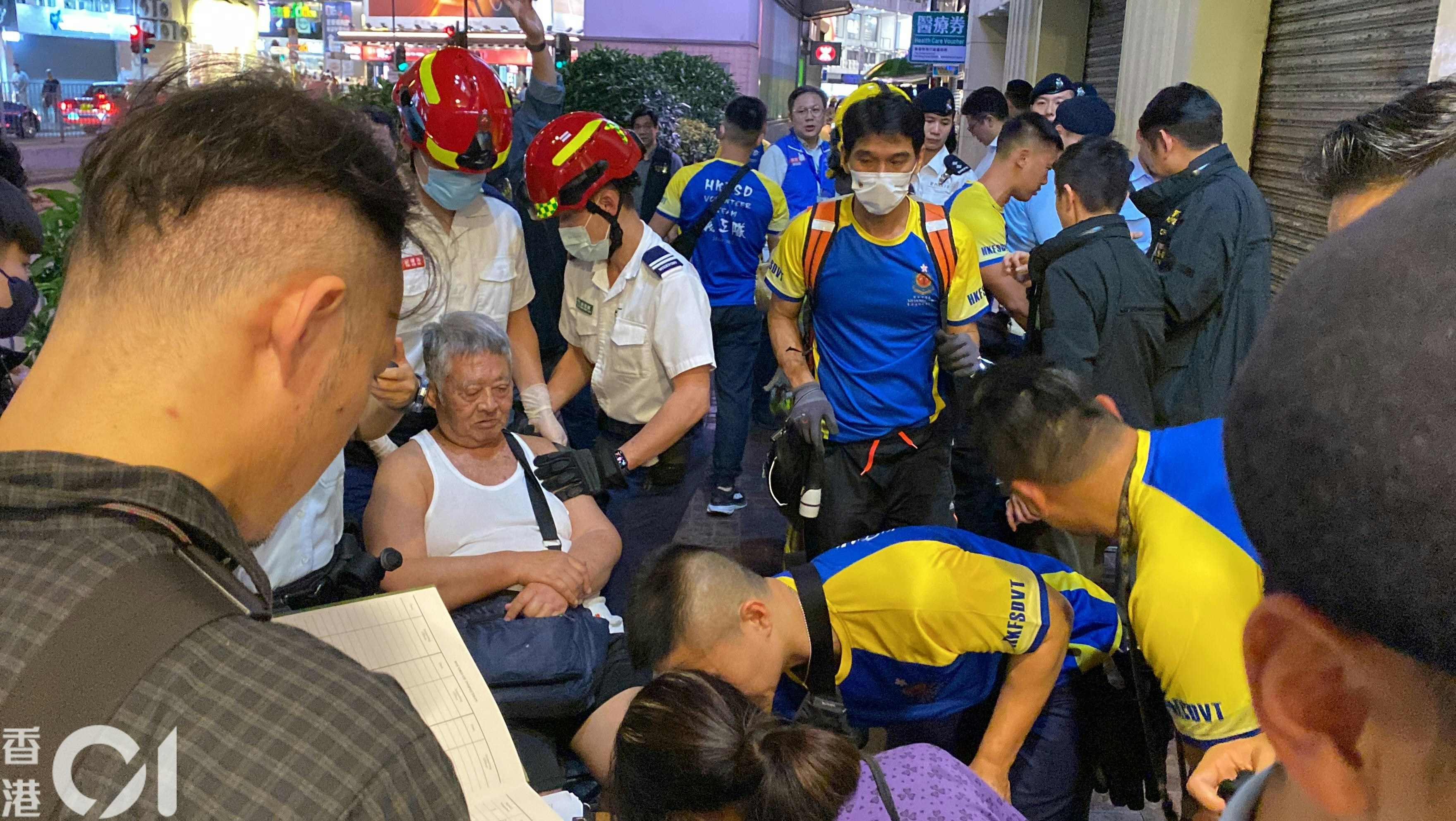 佐敦华丰大厦4月10日发生3级火，造成5死40人伤。香港消防处义工队成员（蓝黄上衣者）晚上在大厦「洗楼」，破门救出一名全日未有进食的老翁（白背心者）。（罗日升摄）