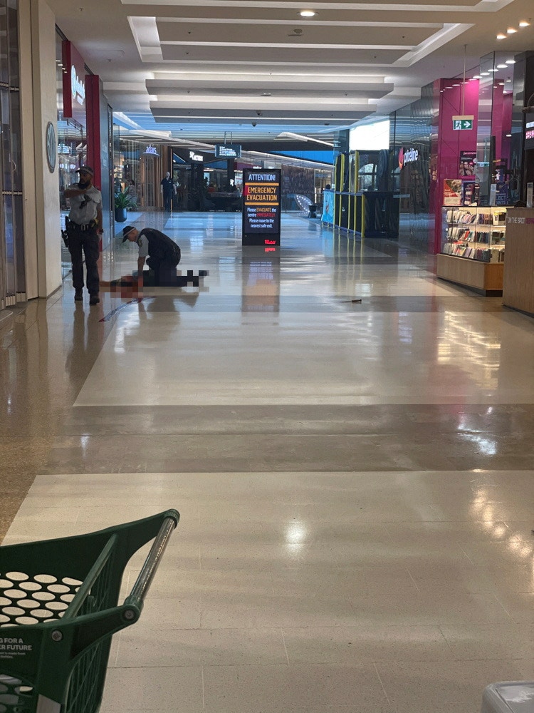 位于澳洲悉尼东部的购物中心Westfield Bondi Junction在2024年4月13日多人被人用刀刺伤，数人死亡。涉案男疑犯被女警开枪击毙。图为已中枪的疑犯倒卧地上，有两名警员在旁。（Reuters）