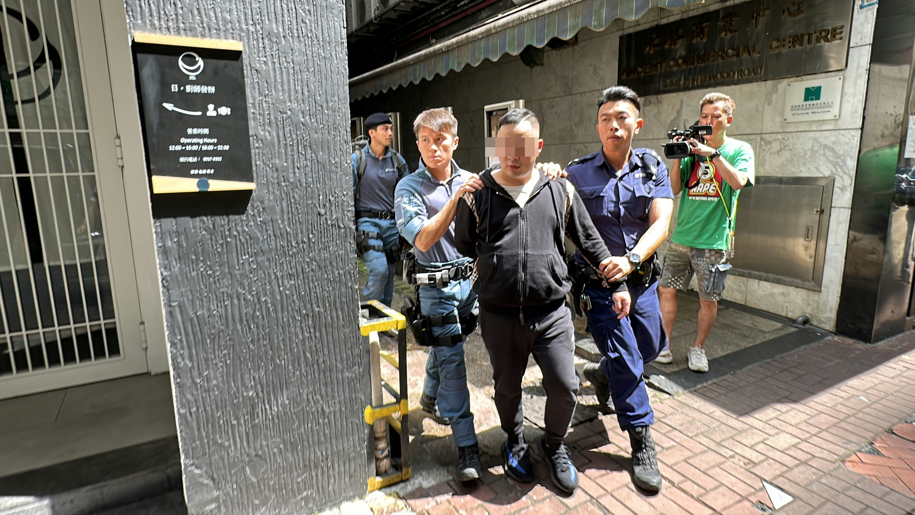 警方接报到场，一群男女于现场接受警方调查，部分人士面向墙壁被警方搜身，一名男子被警方押上警车。（香港01记者摄）