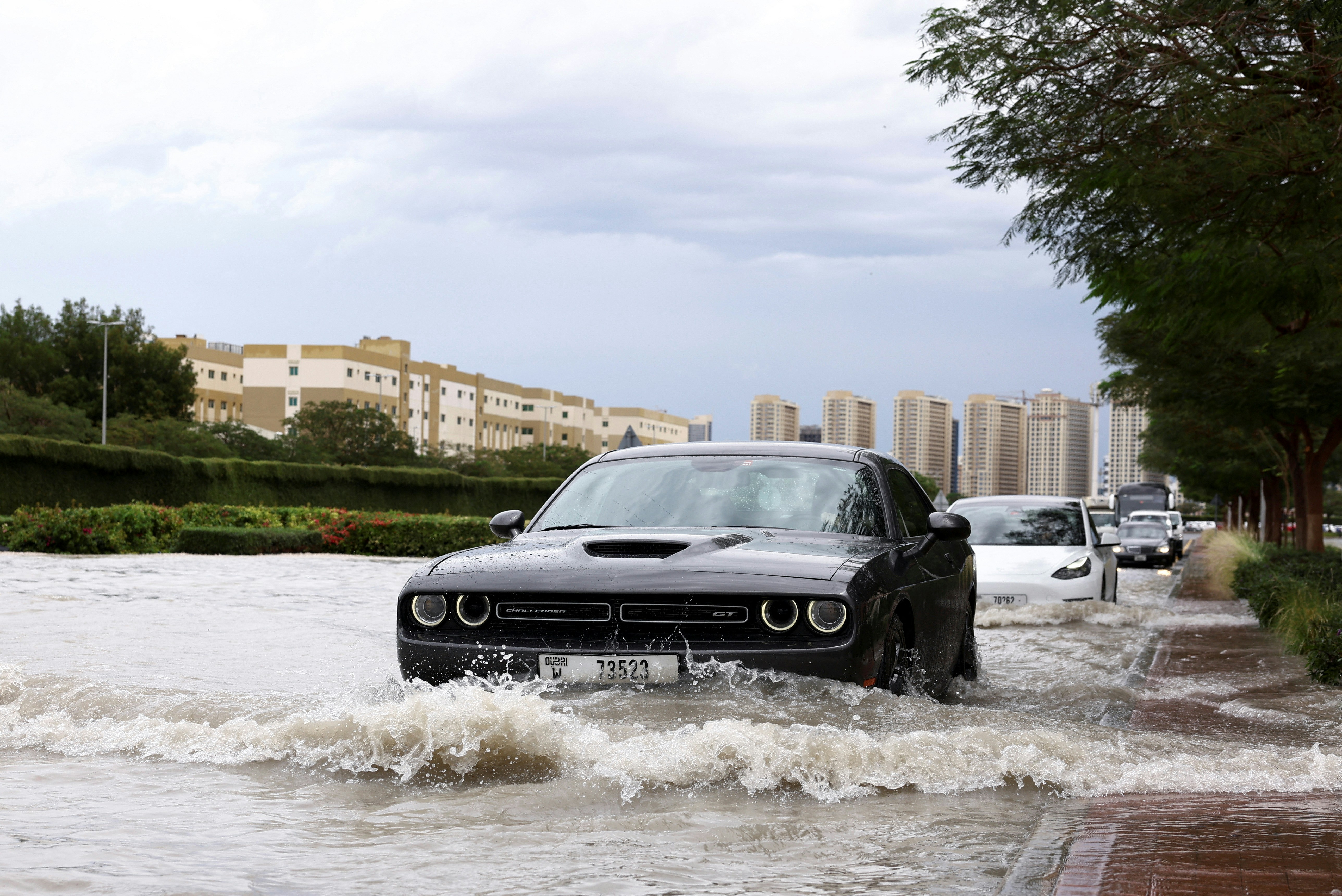 阿联酋杜拜在暴风雨中受灾，图为2024年4月16日，汽车驶过被洪水淹没的街道。（Reuters）