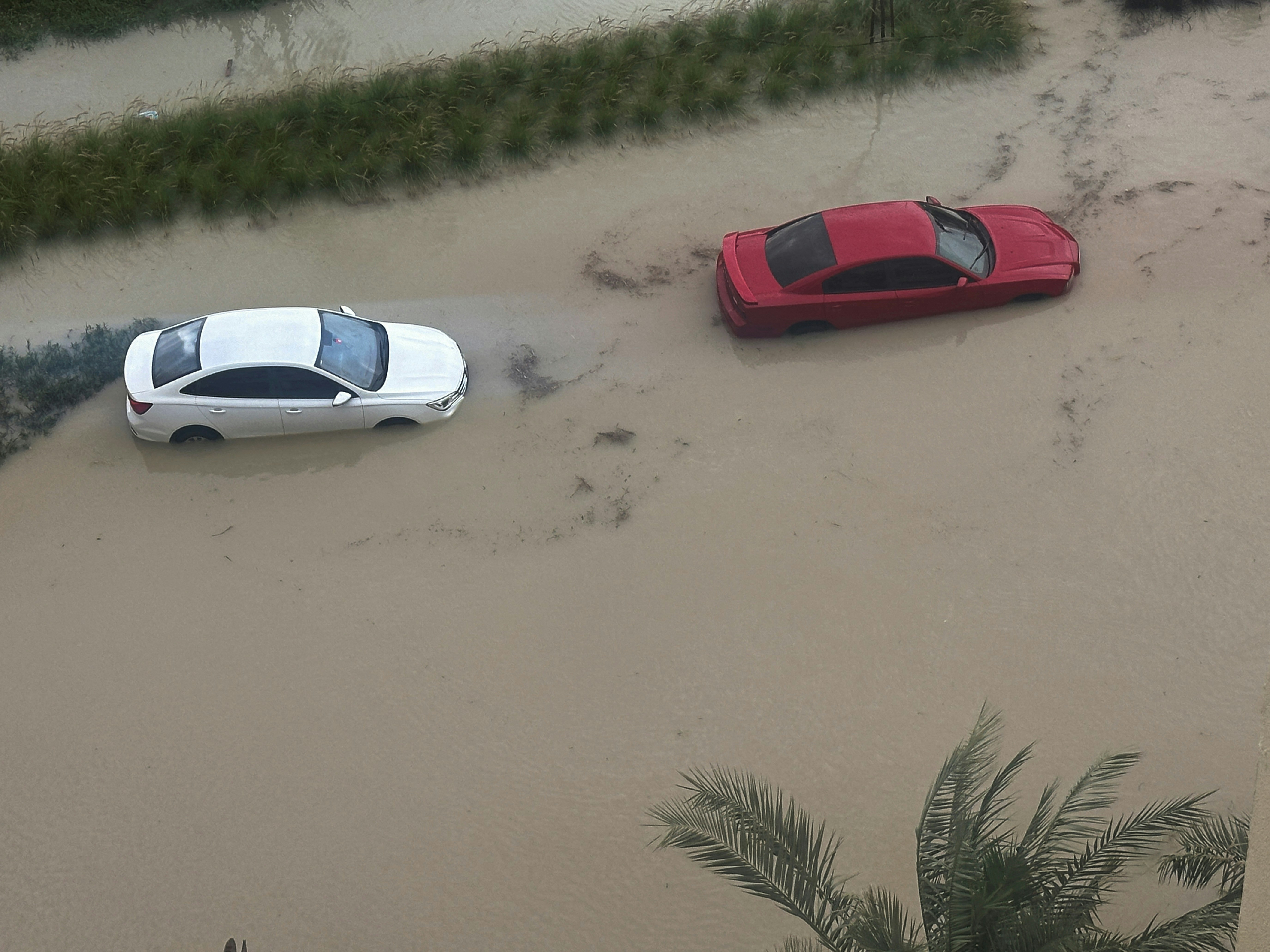 图为2024年4月16日，镜头下在暴雨持续期间，停在阿联酋杜拜已水浸的街道上的汽车。（Reuters）