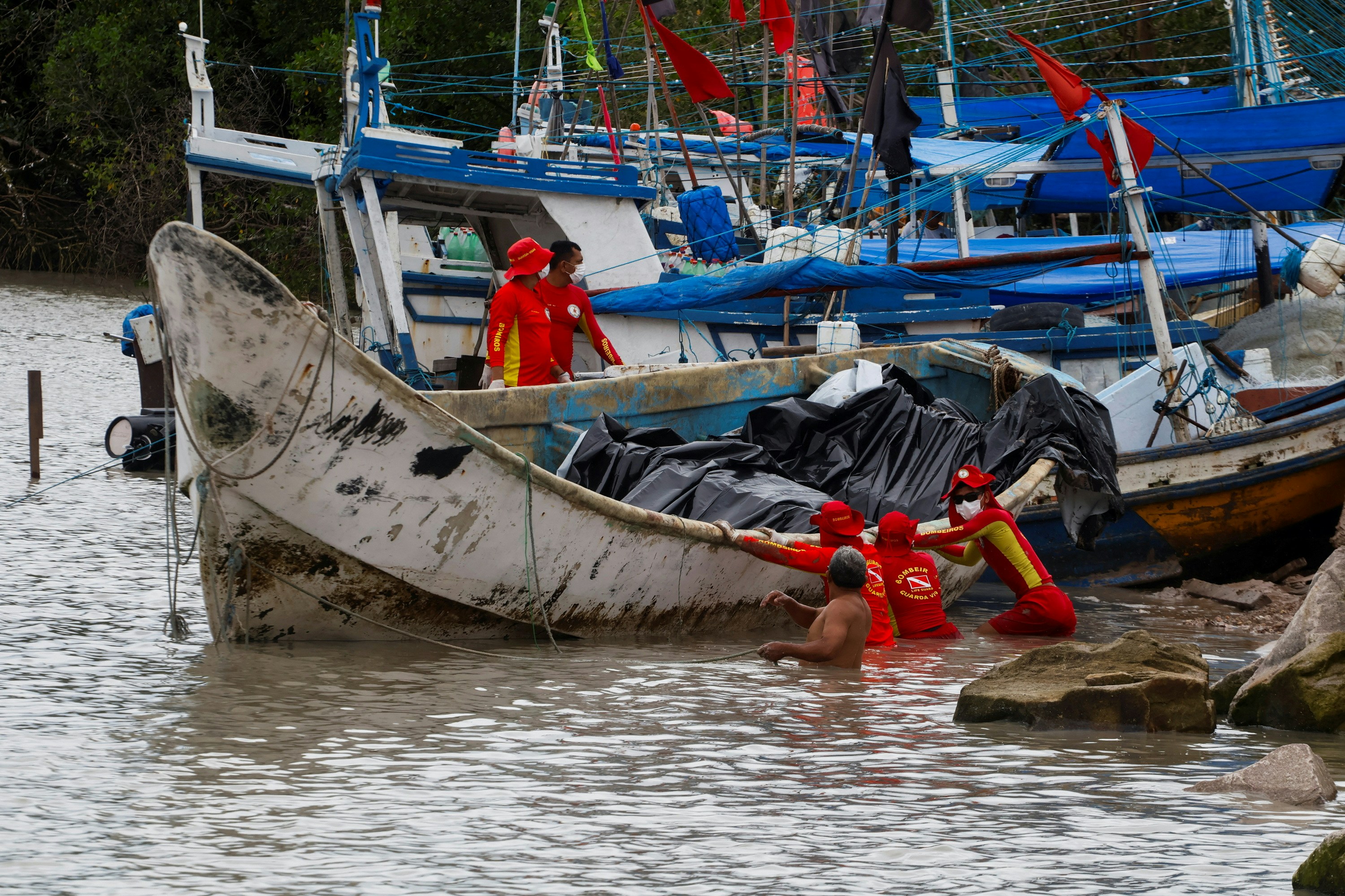 图为2024年4月15日，巴西帕拉州，消防员到场将「鬼船」拖上岸。（Reuters）