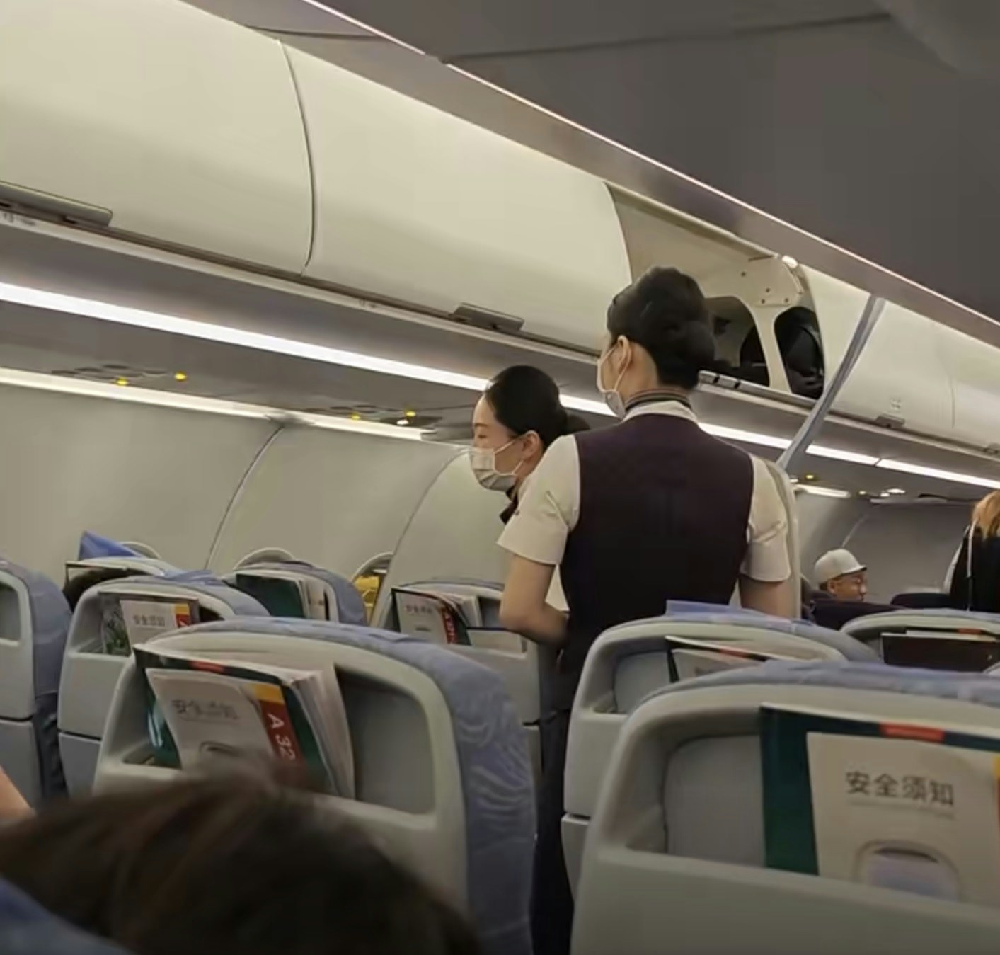 多名乘客質問空姐為何航班折返。(網上影片截圖)