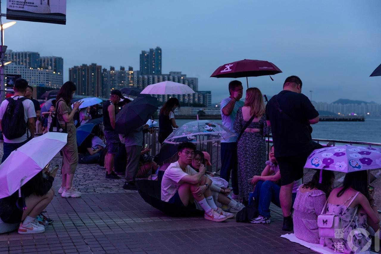 旅发局5月1日晚8时在尖东海旁举行海上烟火表演，在近晚上7时，有大批市民及旅客在行人路上等候观看。不过现场有小雨，不少人开伞。（梁鹏威摄）
