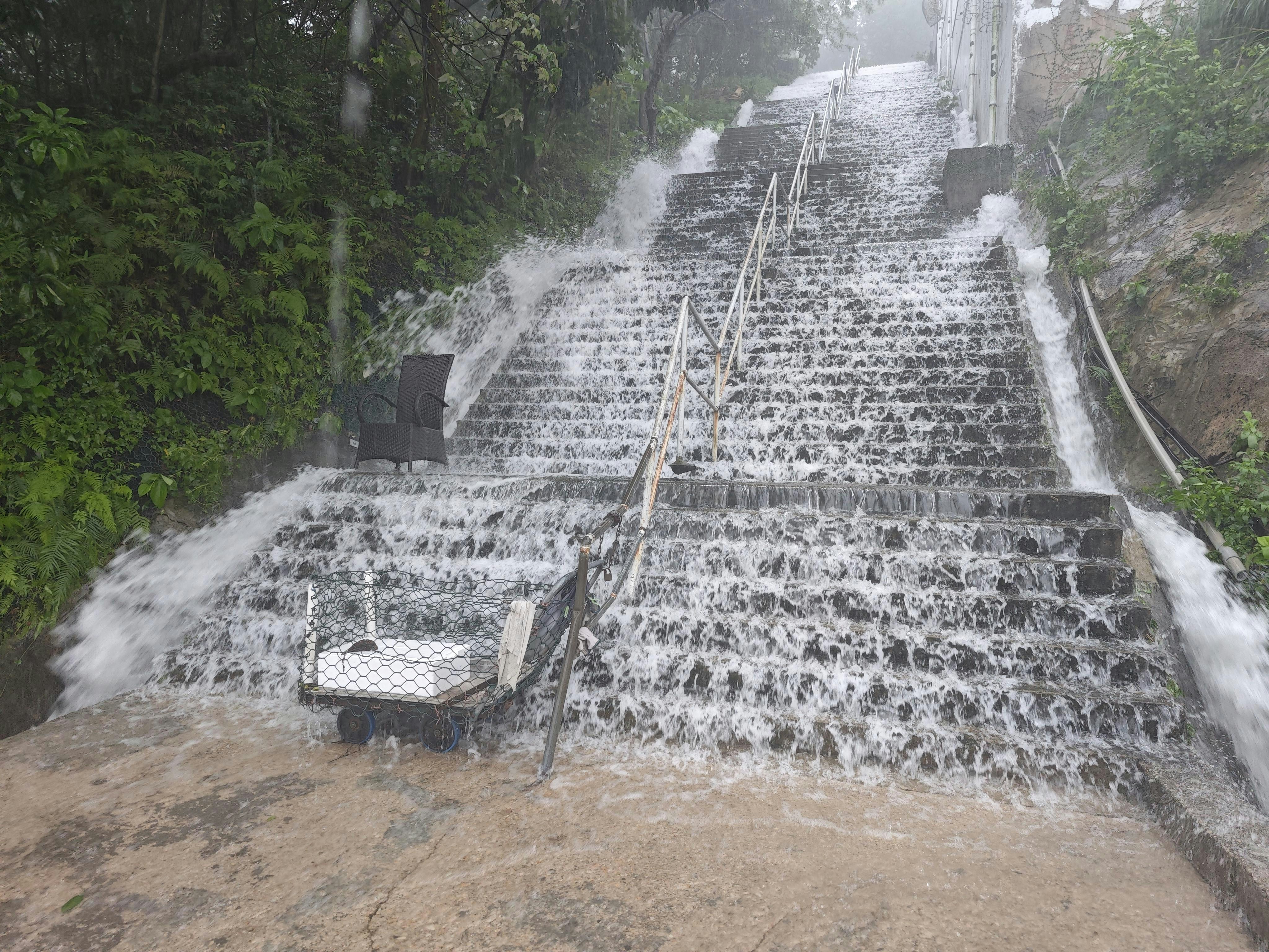 清水湾银岬路一条楼楼梯，雨水如瀑布泻下。
