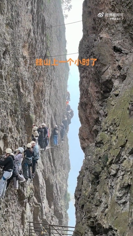 五一假期间，大批在浙江温州雁荡山体验飞拉达攀岩的游客悬挂在半山腰上动弹不得。（影片截图）