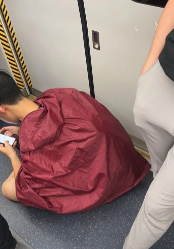疑內地男生坐於港鐵車廂地下，不但阻礙乘客上落，險累長者跌倒遭斥自私。（Dcard圖片）