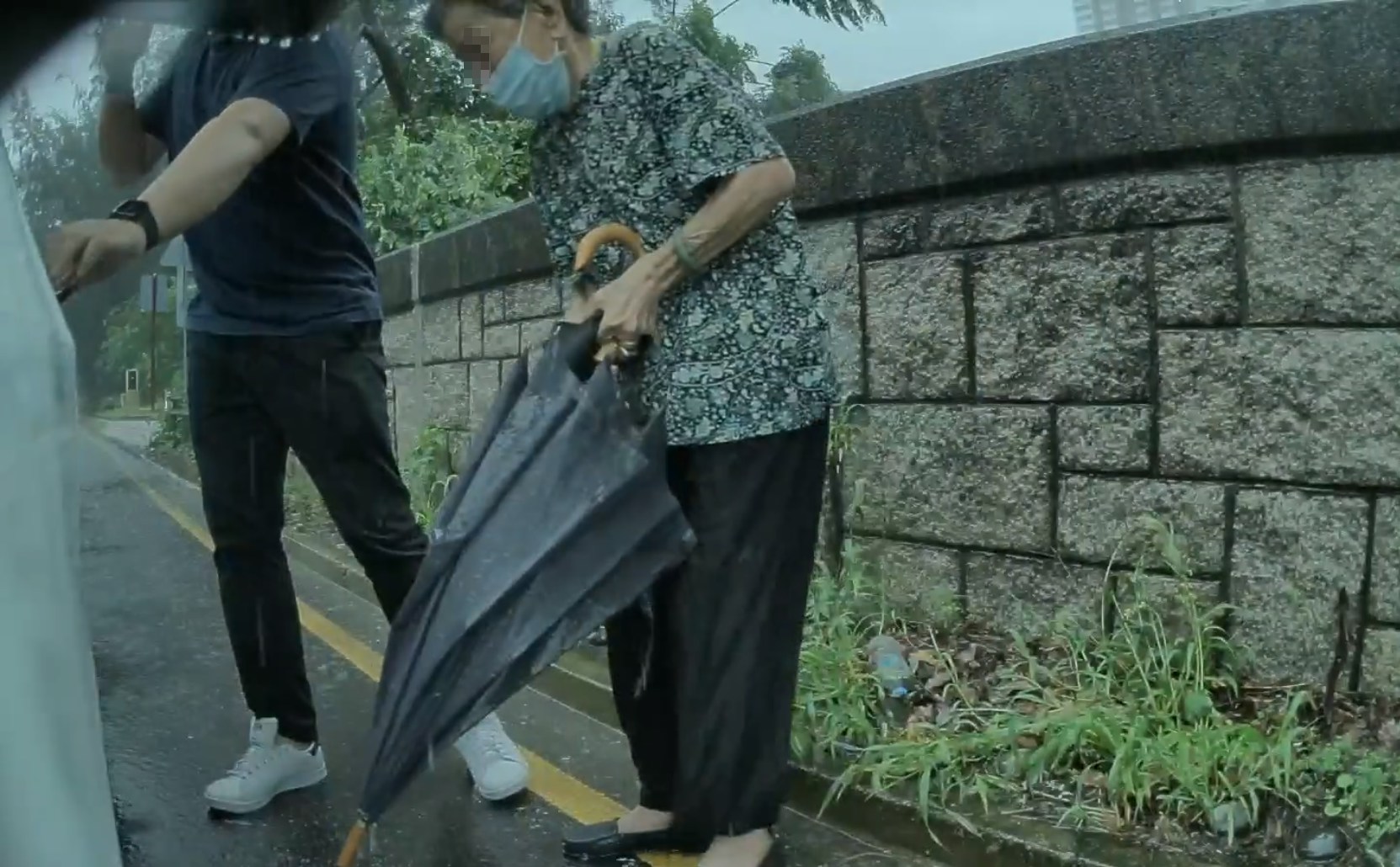 大雨时分，男子邀请老妇上车并载她回家。（大埔 TAI PO Facebook/Leslie Law)
