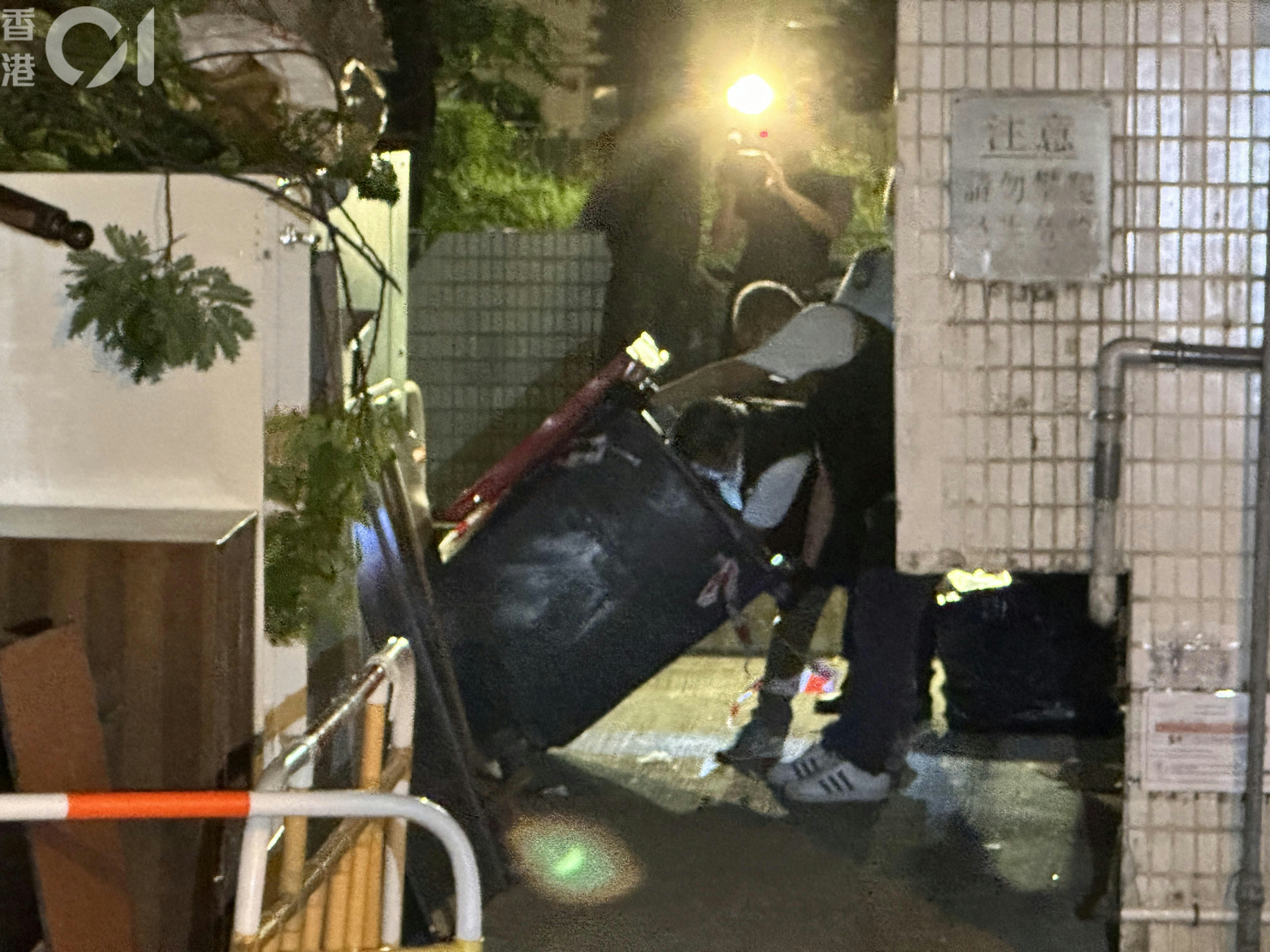 探员在大厦旁一个垃圾桶内，检走床单、衣服等杂物，并带上涉案单位作调查。（王译扬摄）