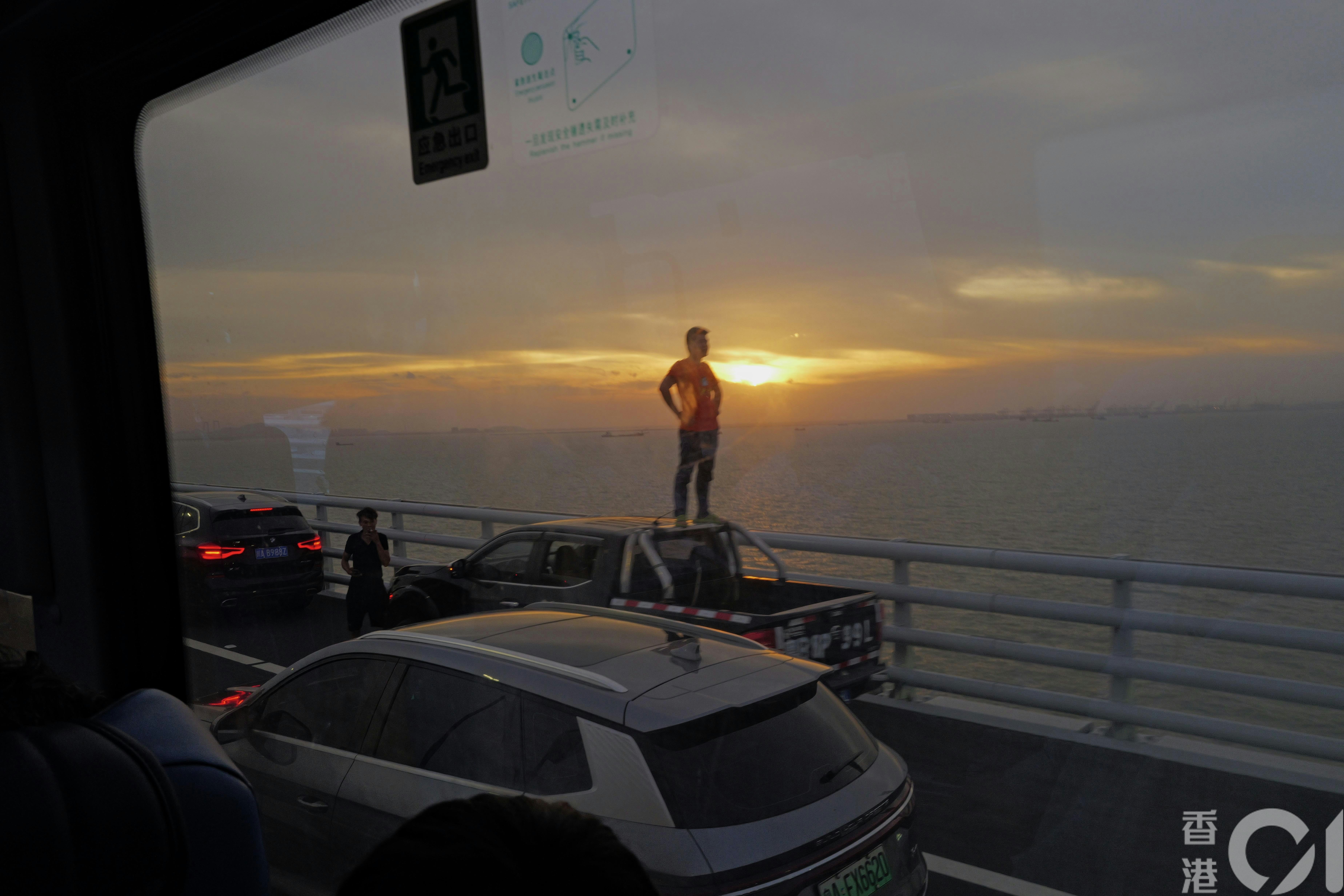 虽然深中通道订明全程不能停车拍摄风景，但途中却有不少车停在路边拍日落，更有人站在车上摆拍。（欧嘉乐摄）