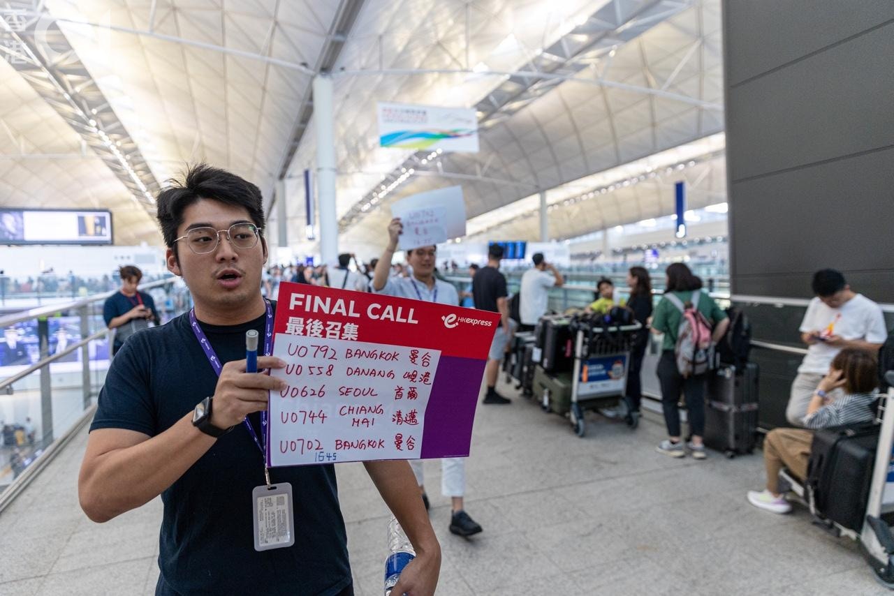 有航空公司職員舉指示牌，協助市民辦理登機手續。（梁鵬威攝）