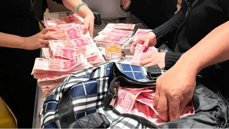 相片見到，當時60萬人民幣現金全是100人民幣（約109港元）鈔票，雖然枱面上已疊起一棟棟100人民幣鈔票，但袋裏仍有大量鈔票未取出，店員正忙於點算金額。（網上圖片）