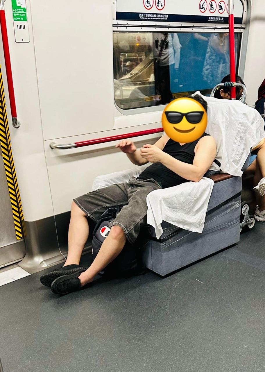 身穿黑色背心的男子乘搭港鐵，相信用手推車搬運1人座位，就地取材直接坐上去，由於座位比較長身，所以坐上去看似舒服寫意。（讀者林小姐提供）