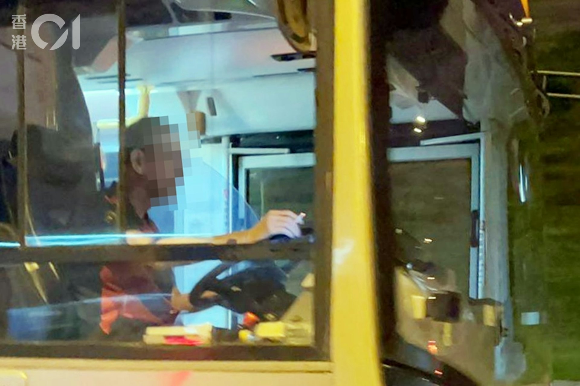 一名巴士車長在巴士行駛期間,手持懷疑點著的香煙,並將手擱在打開的車窗上。(讀者提供圖片) 一名巴士車長在巴士行駛期間,手持懷疑點著的香煙,並將手擱在打開的車窗上。(讀者提供圖片)