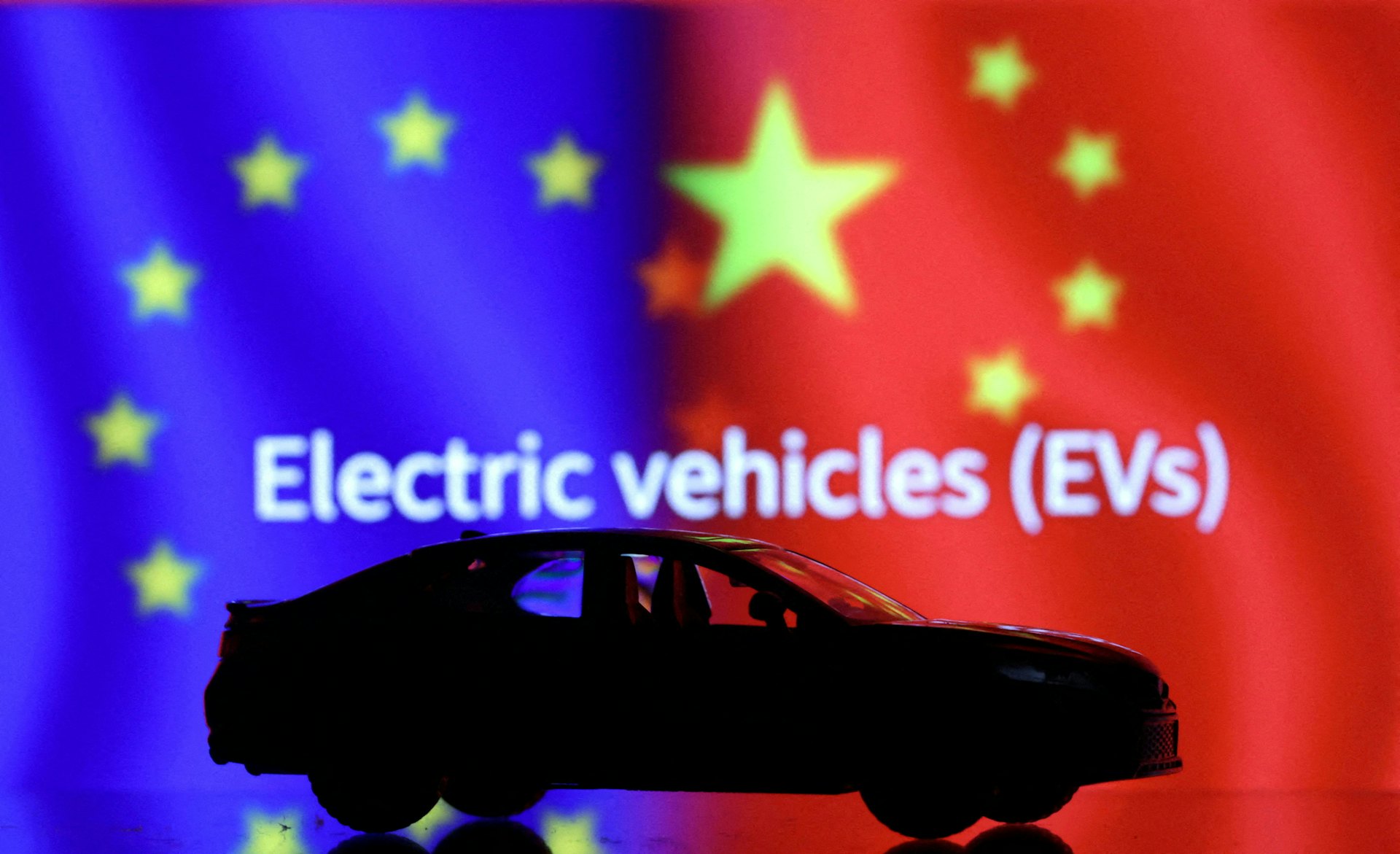2023年9月26日,圖為路透社設計的圖片,其中一輛電動車模型後可見到歐盟旗幟與中國國旗。