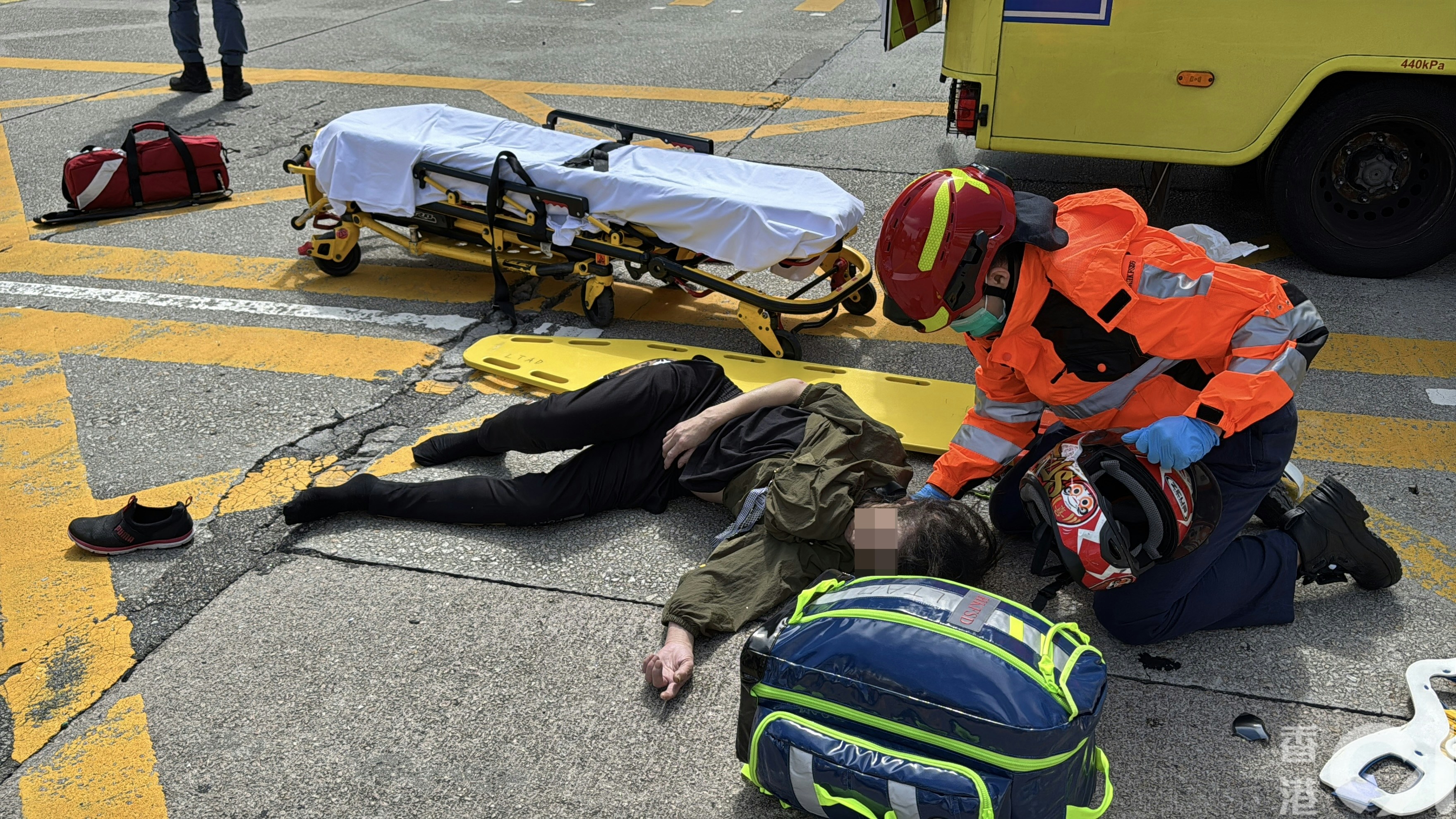 女傷者倒地受傷，救護員為她檢查傷勢。