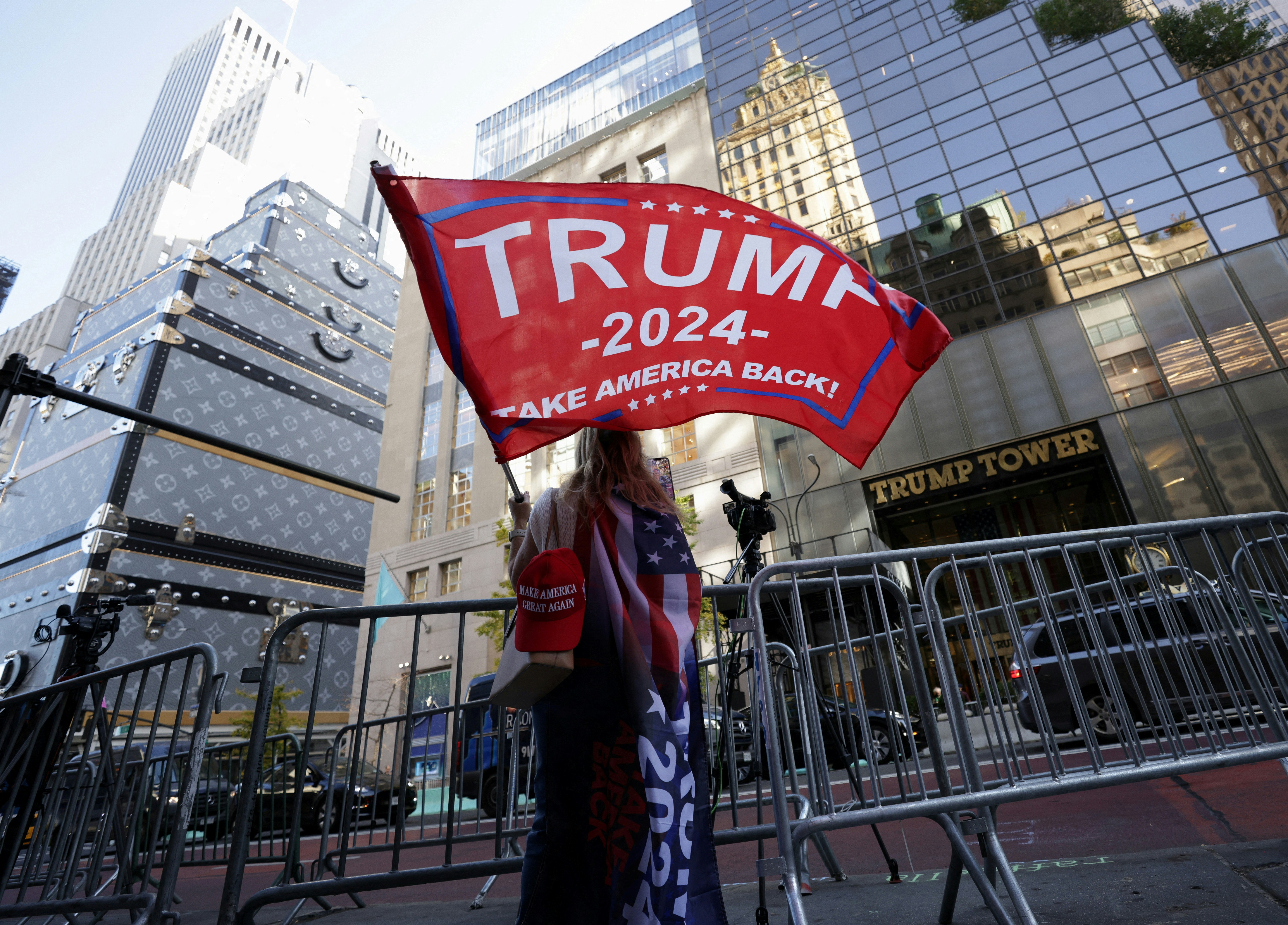 2024年11月6日，美國前總統特朗普（Donald Trump）勝出大選後，支持者在紐約市的特朗普大樓（Trump Tower）外，揮舞寫有其名字的旗幟。（Reuters）