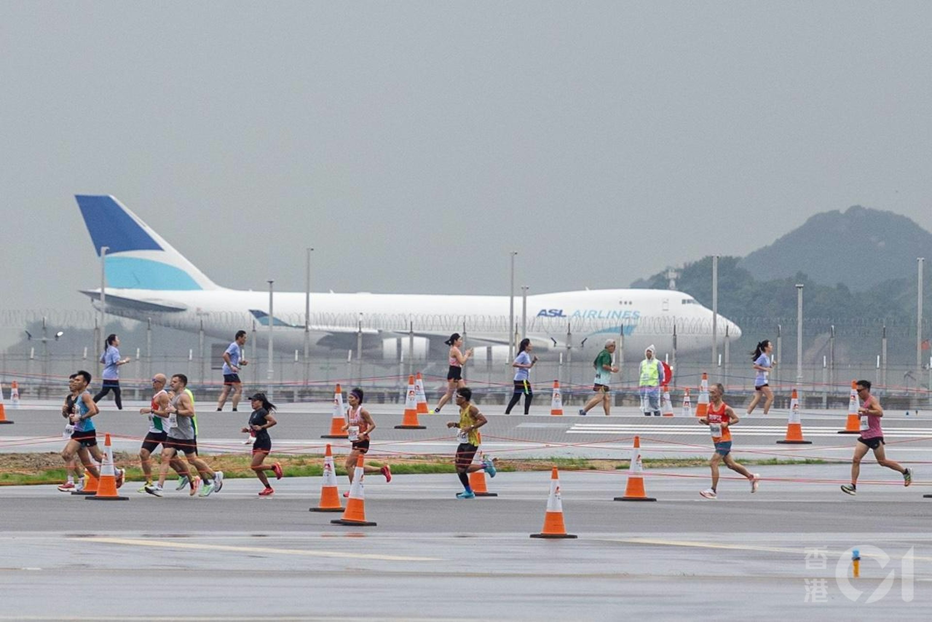 機管局在11月17日在趁機場中跑道未啟用前,舉行「渣打香港馬拉松:三跑道系統十公里國際賽」,是機場繼1998年後再次上演長跑賽,期間有飛機在北跑道如常降落。(梁鵬威攝) 機管局在11月17日在趁機場中跑道未啟用前,舉行「渣打香港馬拉松:三跑道系統十公里國際賽」,是機場繼1998年後再次上演長跑賽,期間有飛機在北跑道如常降落。(梁鵬威攝)