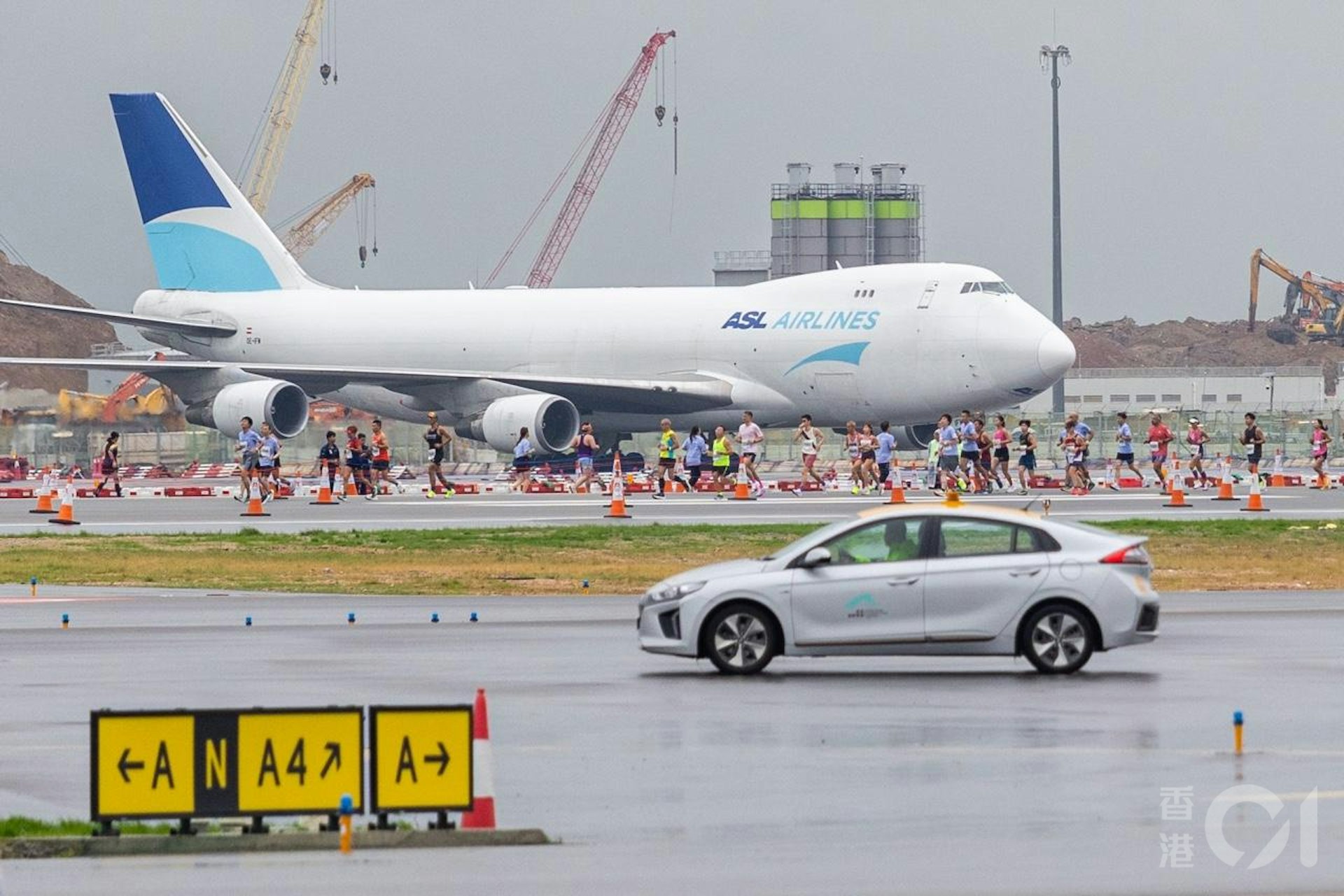 機管局在11月17日在趁機場中跑道未啟用前,舉行「渣打香港馬拉松:三跑道系統十公里國際賽」,是機場繼1998年後再次上演長跑賽,期間有飛機在北跑道如常降落及滑行至T1客運廊。(梁鵬威攝) 機管局在11月17日在趁機場中跑道未啟用前,舉行「渣打香港馬拉松:三跑道系統十公里國際賽」,是機場繼1998年後再次上演長跑賽,期間有飛機在北跑道如常降落及滑行至T1客運廊。(梁鵬威攝)