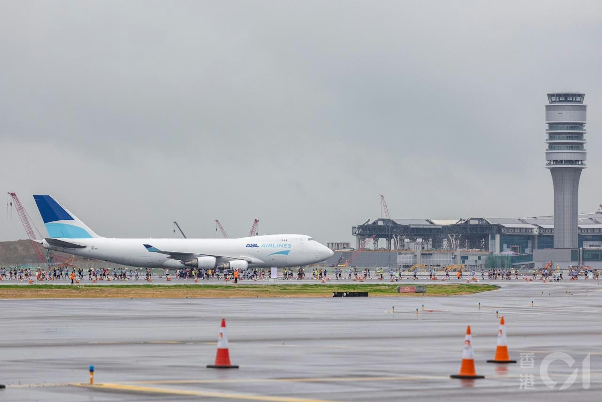 機管局在11月17日在趁機場中跑道未啟用前,舉行「渣打香港馬拉松:三跑道系統十公里國際賽」,是機場繼1998年後再次上演長跑賽,期間有飛機在北跑道如常降落及滑行至T1客運廊,後方是正在興建的T2客運廊。(梁鵬威攝) 機管局在11月17日在趁機場中跑道未啟用前,舉行「渣打香港馬拉松:三跑道系統十公里國際賽」,是機場繼1998年後再次上演長跑賽,期間有飛機在北跑道如常降落及滑行至T1客運廊,後方是正在興建的T2客運廊。(梁鵬威攝)