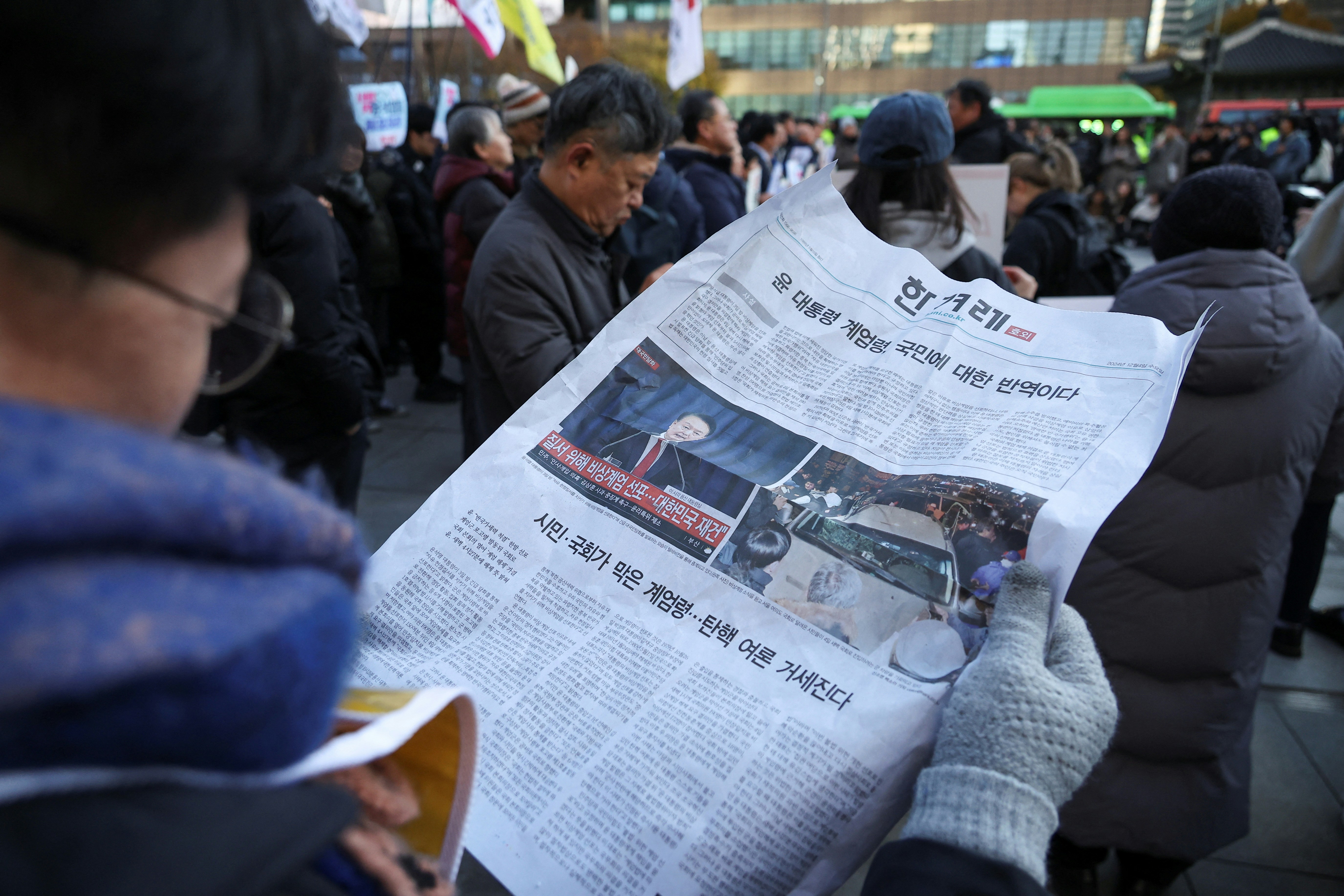 韓國解除戒嚴令後, 2024年12月4日，韓國首爾，一名男子在呼籲罷免韓國總統尹錫悅的集會上閱讀報紙。(Reuters)