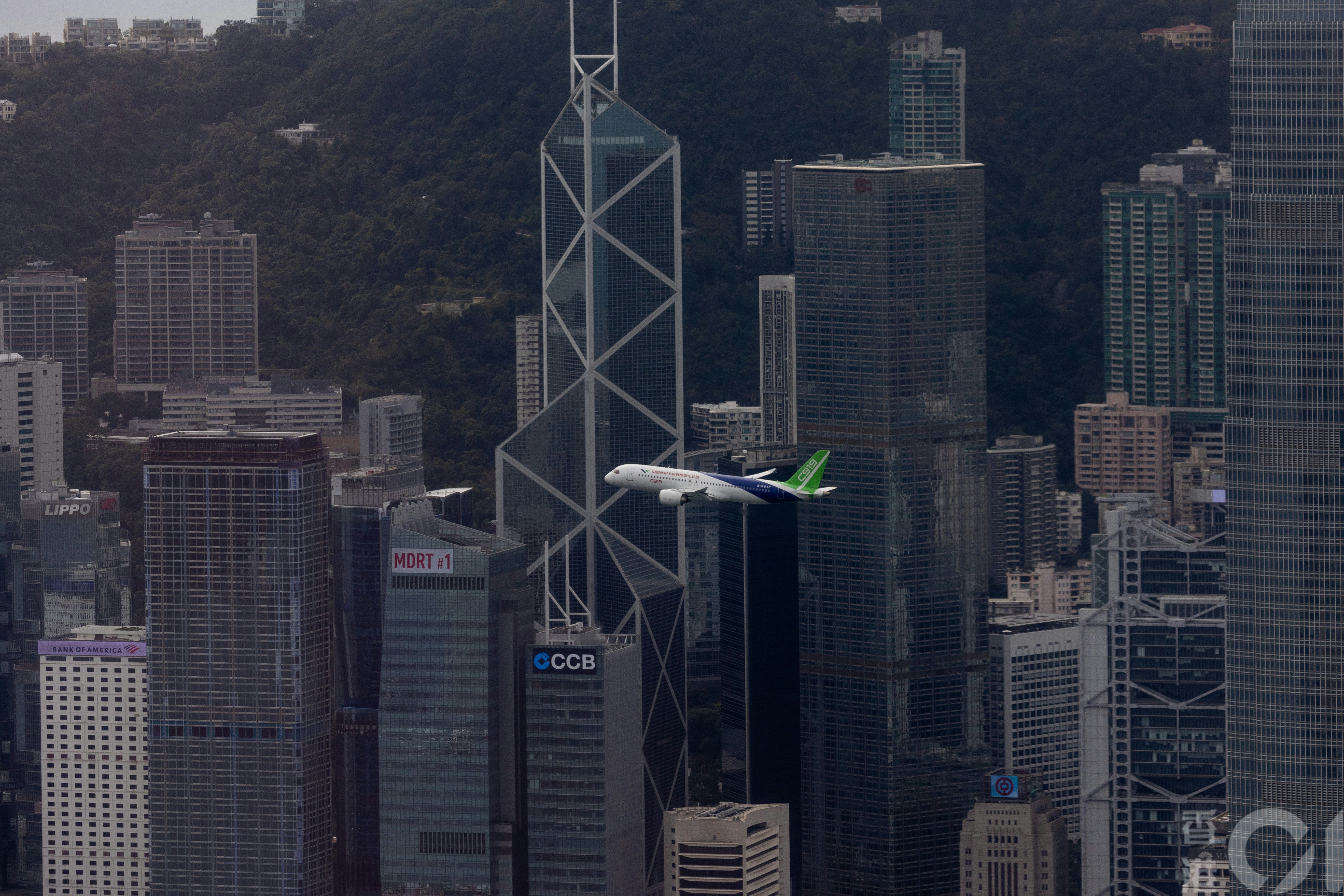 The picture shows the C919 conducting a flight demonstration on December 16, 2024, soaring twice over Victoria Harbour at altitudes of 1,500 feet and 1,000 feet respectively. Looking out from the sky100 Hong Kong Observation Deck, the C919 seems to be integrated into the skyscrapers on both sides of the Victoria Harbour. (Photo by Xia Jialang)