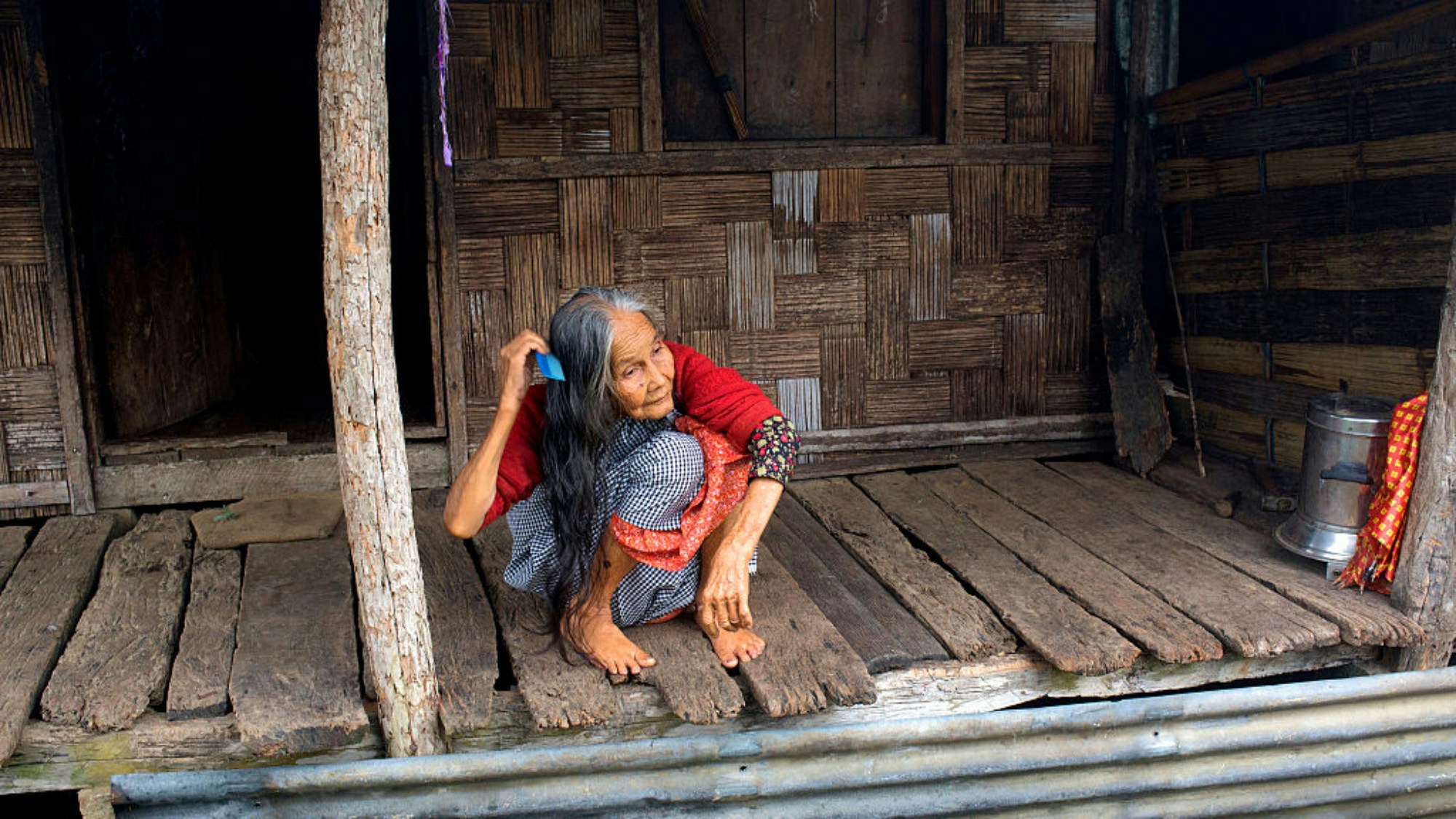 2016年5月15日，印度梅加拉亞邦（Meghalaya）Mawlynnong村莊的一間房屋前，一名老婦人正在梳頭。（Getty）