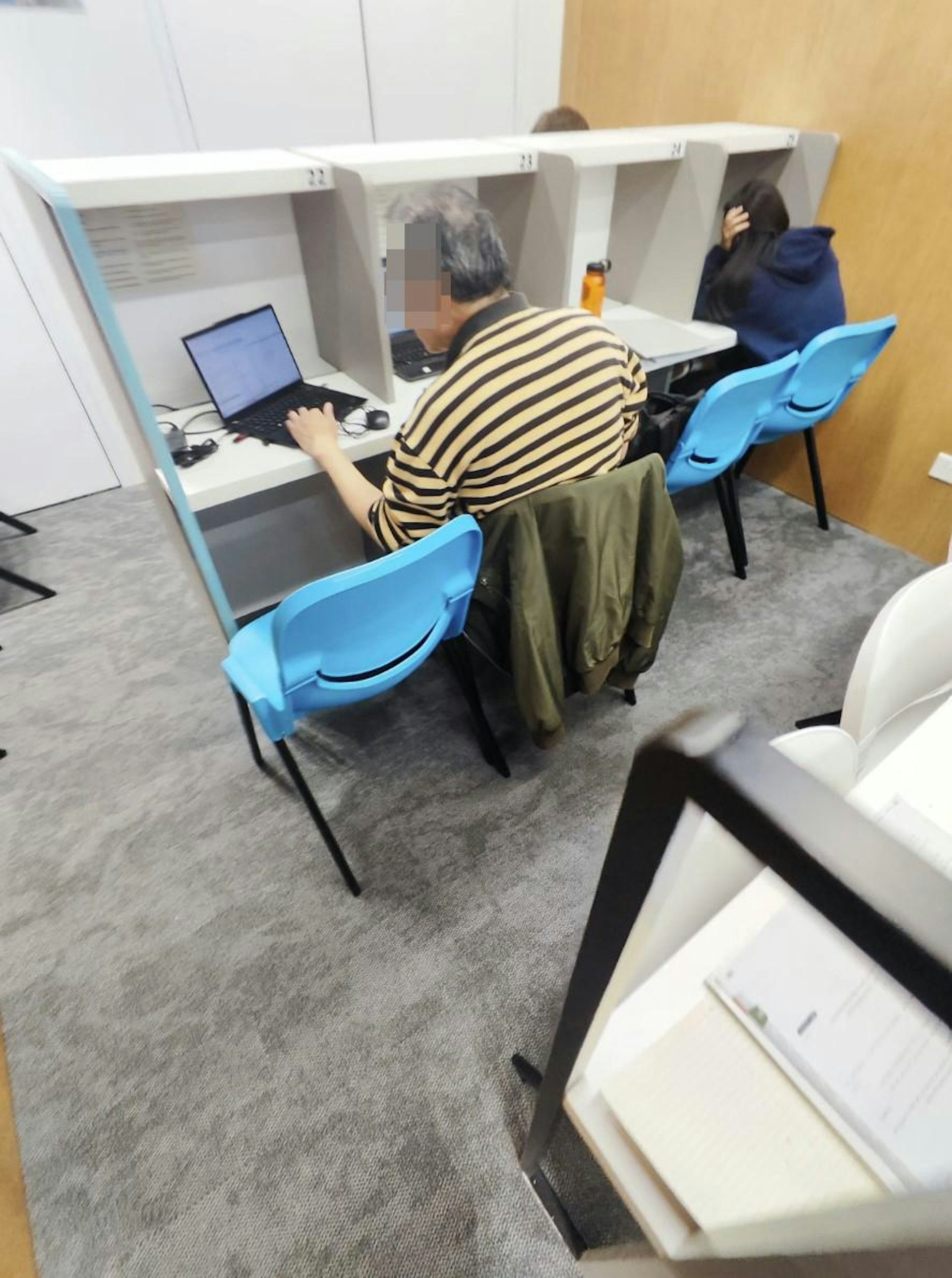阿伯坐在中間座位,開啟1部電腦,在左邊位置極專心地使用另1部電腦,右邊擺放其個人物品包括水樽。(Threads圖片) 阿伯坐在中間座位,開啟1部電腦,在左邊位置極專心地使用另1部電腦,右邊擺放其個人物品包括水樽。(Threads圖片)