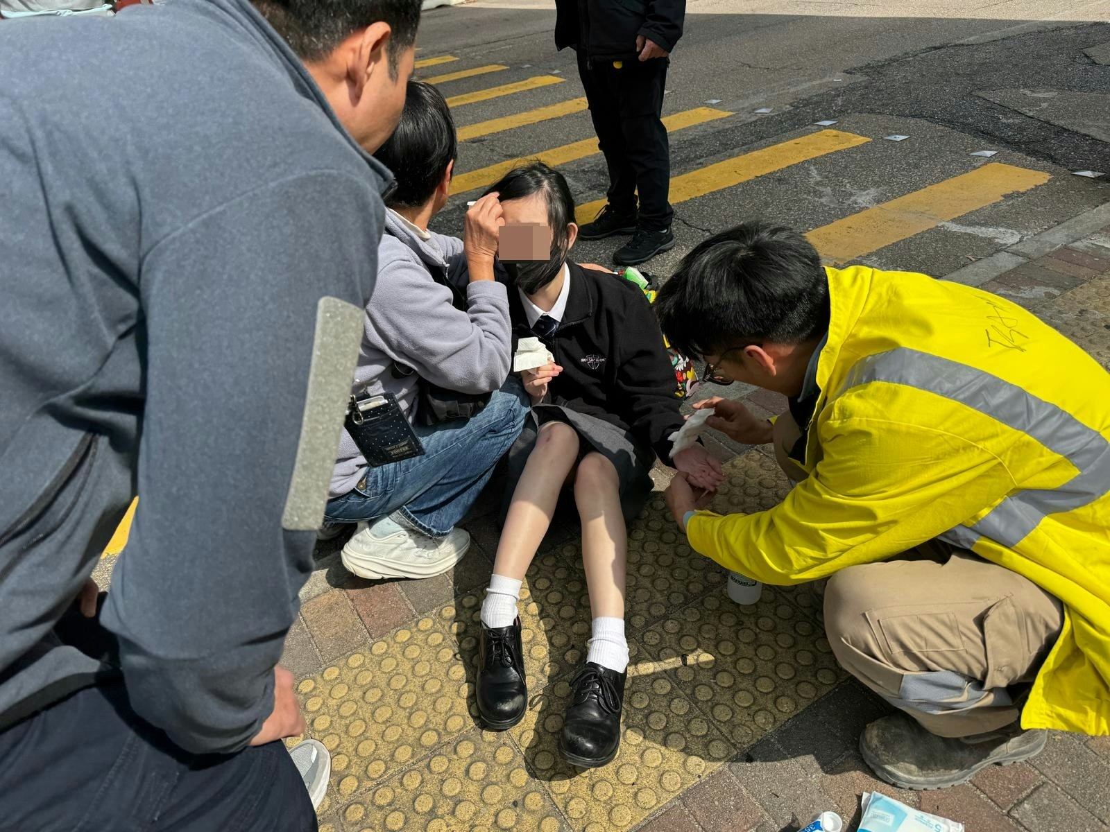 受傷女學生坐在地上接受治療。（讀者提供）