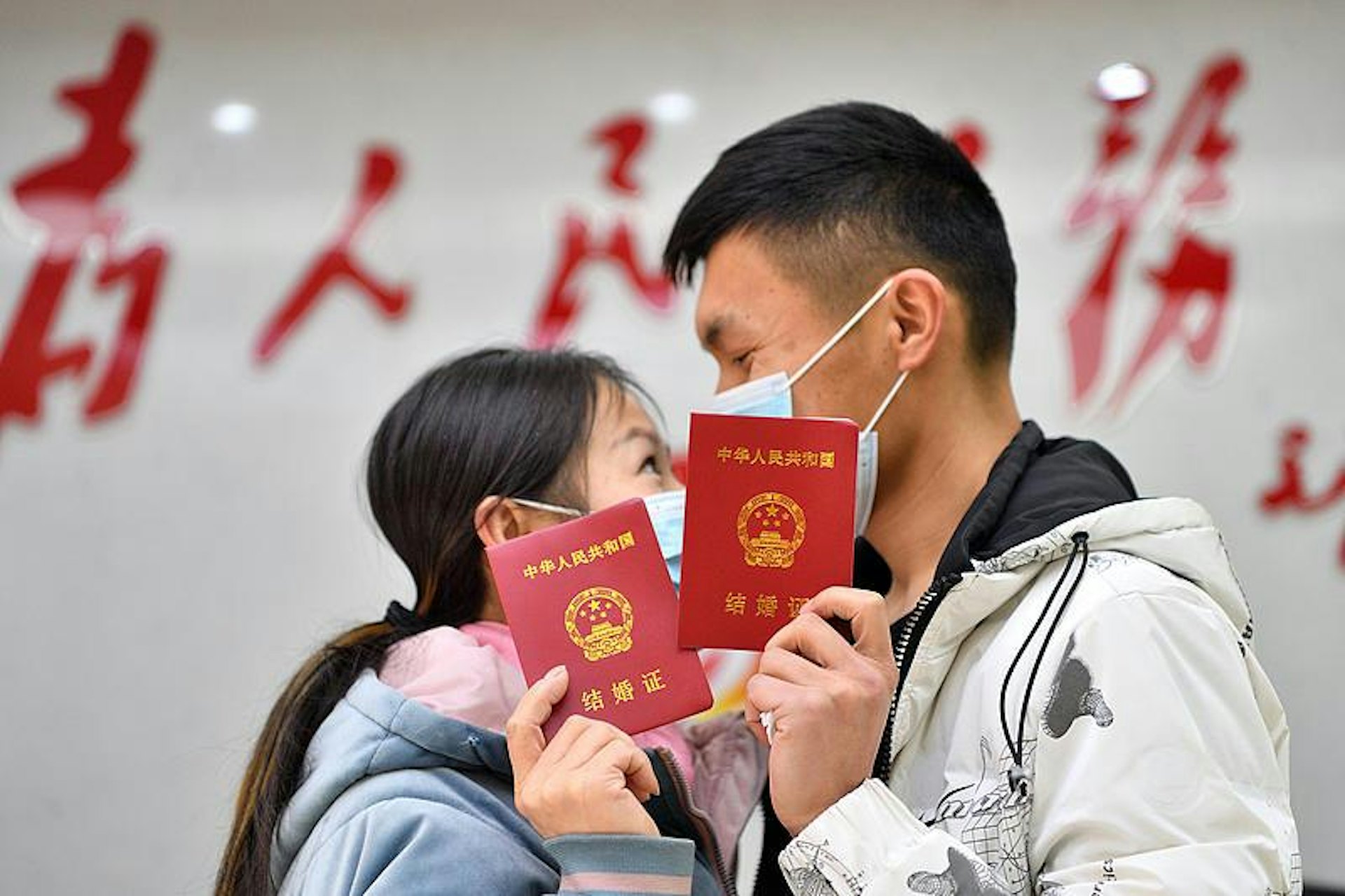 2022年2月22日,在湖北省襄阳市保康县民政局婚姻登记处,一对新人在领取结婚证后合影留念。(视觉中国) 2022年2月22日,在湖北省襄阳市保康县民政局婚姻登记处,一对新人在领取结婚证后合影留念。(视觉中国)