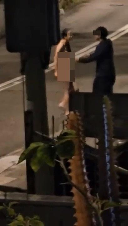 本港網絡瘋傳1段影片，指有一對情侶深夜在馬路上吵架，其中女方脫至全裸怒摑男方一把掌，並不斷逼迫男方報警。（影片截圖）