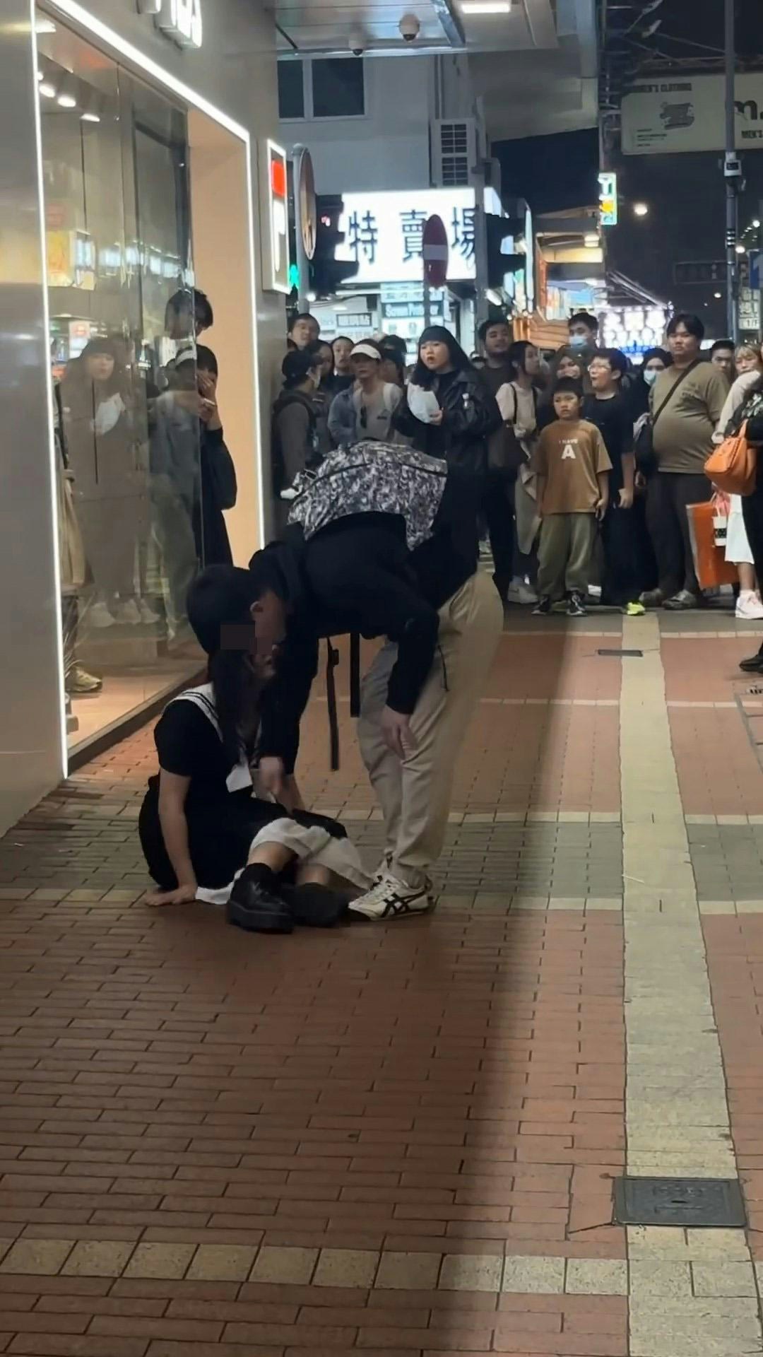 長髮女生坐在地上，疑似男友想扶她起身，惟長髮女大力推開男方，聲嘶力竭咆哮：「走啊！」（影片截圖）