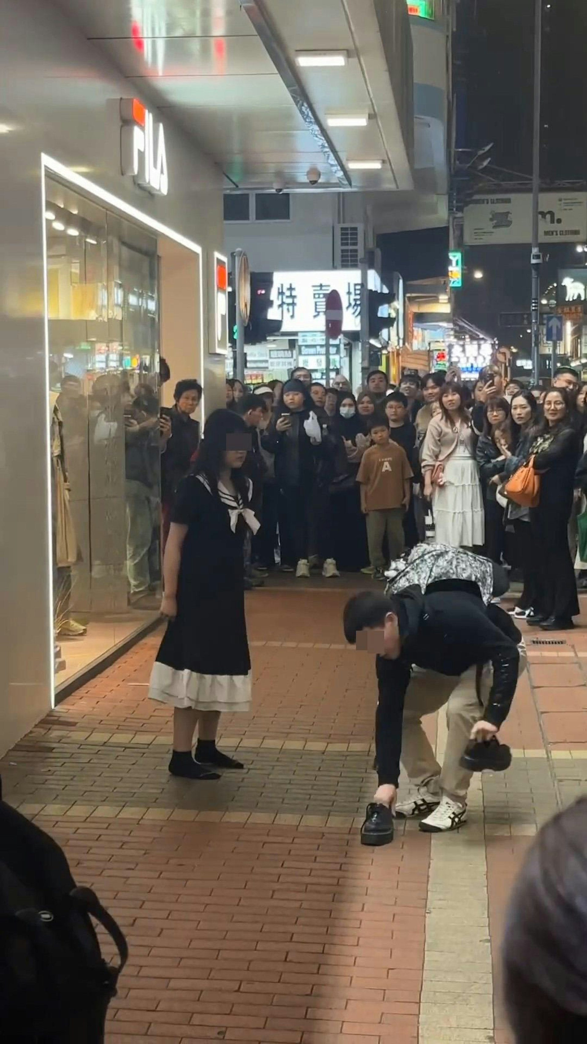 男方邊撿起長髮女脫下的鞋子,邊靠近女方,長髮女則向後退,與男方保持距離。(影片截圖)