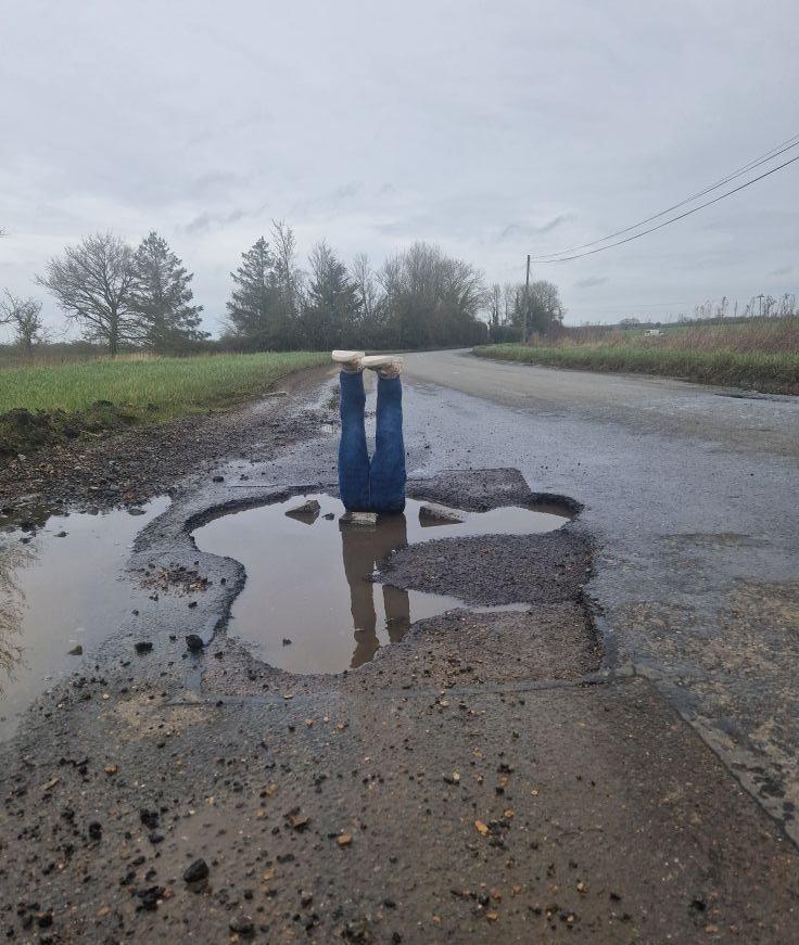 英國劍橋郡一男子因為當地一條道路缺乏管理而失修、坑窪不平，令行車者屢受害，最終他突發奇想，在一個坑中倒置假腳，形似有人栽倒在坑中。（James Coxall）