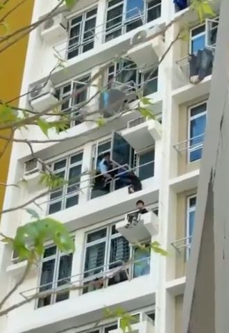 警員在單位內伸出手，協助坐在4樓外牆的男童返回室內。（讀者提供）