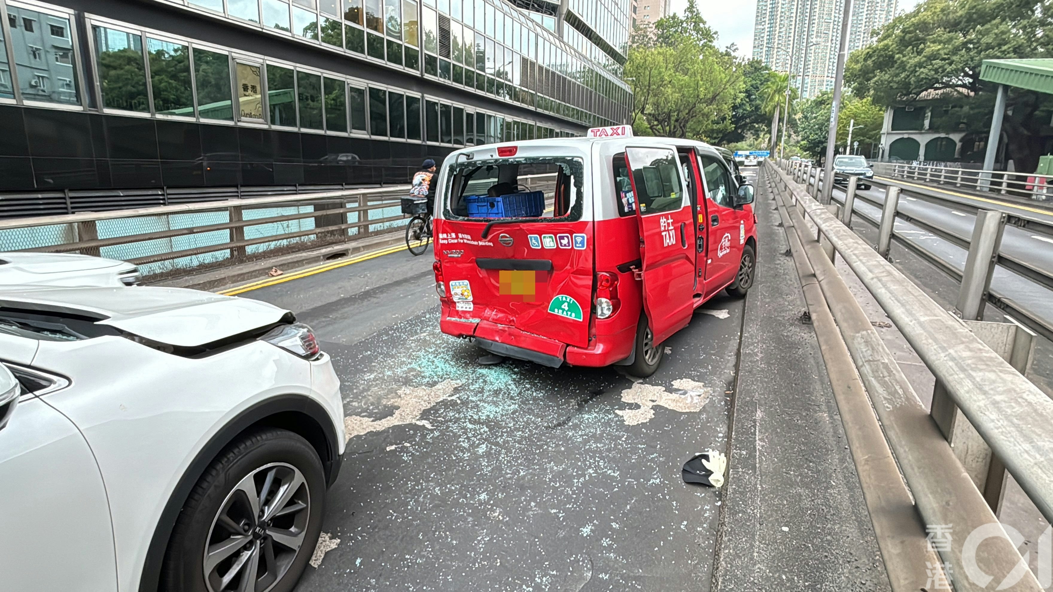 一輛白色私家車撞向前方俗稱「小露寶」紅的，的士車頭及車尾同撞至凹陷，車尾玻璃碎滿一地。（馬耀文攝）