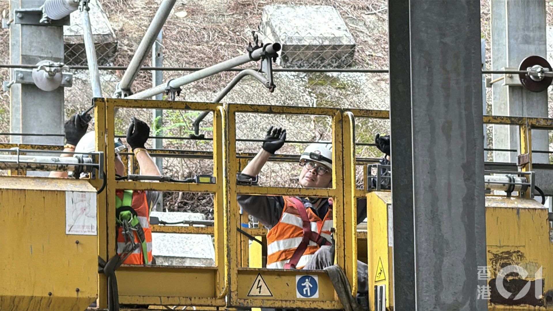 一輛工程車停在東鐵綫沙田站往火炭站方向的路軌上,距離火炭站大約500米。現場所見懷疑因為升降台無法降落,直接行車會損毀電纜,工程人員登上升降台,徒手托起電纜,再通知同事行車,逐步解困。(蔡正邦攝) 一輛工程車停在東鐵綫沙田站往火炭站方向的路軌上,距離火炭站大約500米。現場所見懷疑因為升降台無法降落,直接行車會損毀電纜,工程人員登上升降台,徒手托起電纜,再通知同事行車,逐步解困。(蔡正邦攝)