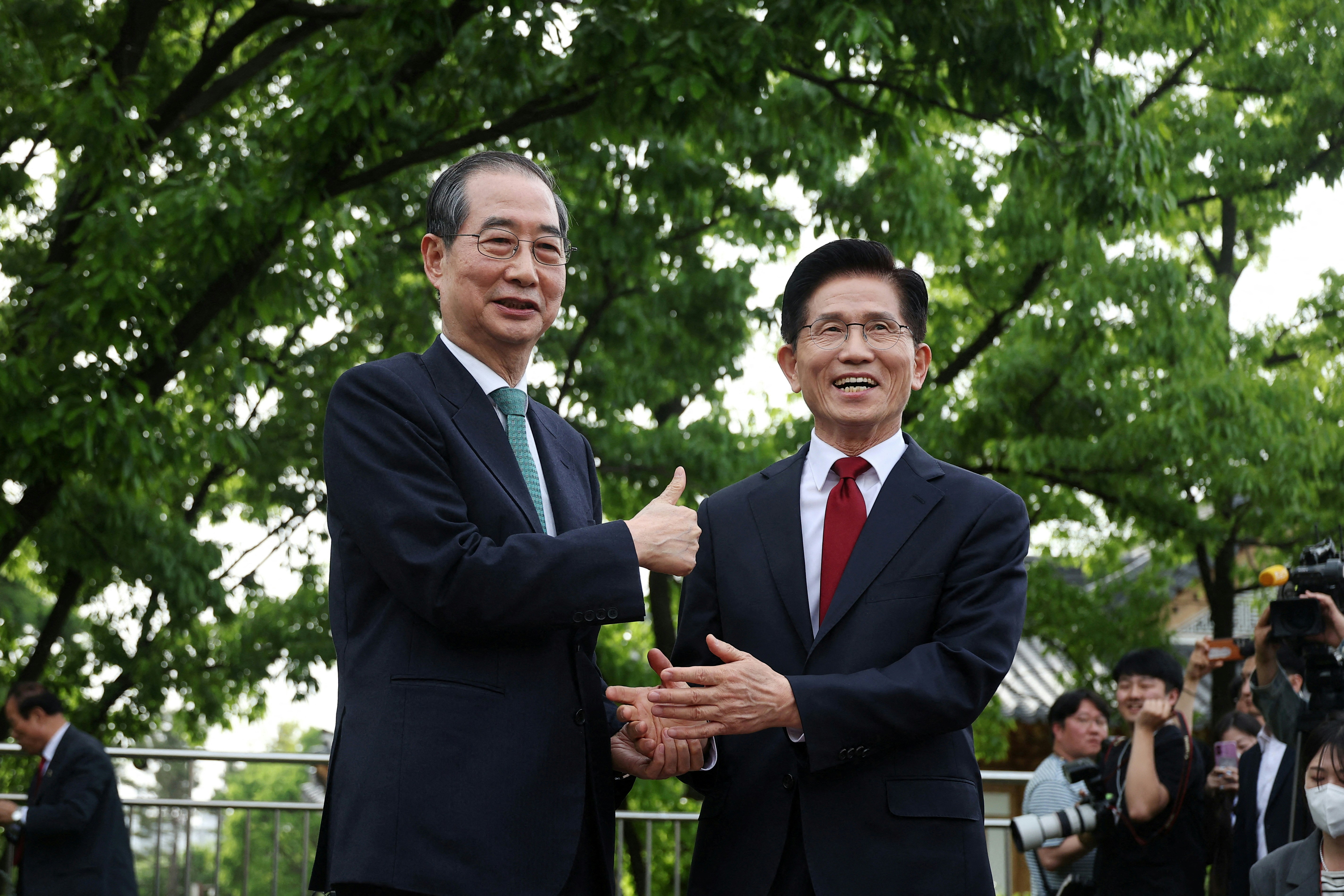 2025年5月8日，韓國首爾，執政國民力量黨總統候選人金文洙（右）與前總理韓悳洙（左）就合併候選人工作進行磋商時握手。（Reuters）