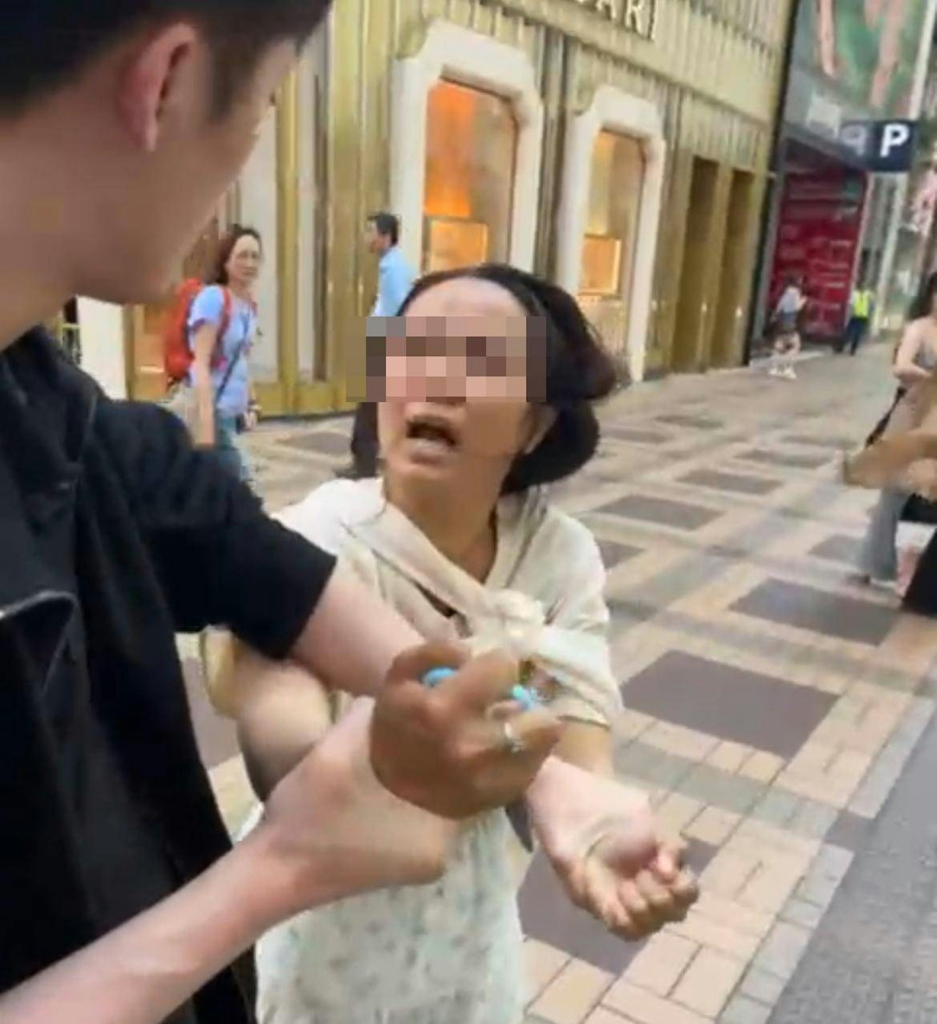 涉案女子手持一把藍色剪刀,一名黑衫男途人上前將其捉住制止。(傷者朋友提供) 涉案女子手持一把藍色剪刀,一名黑衫男途人上前將其捉住制止。(傷者朋友提供)