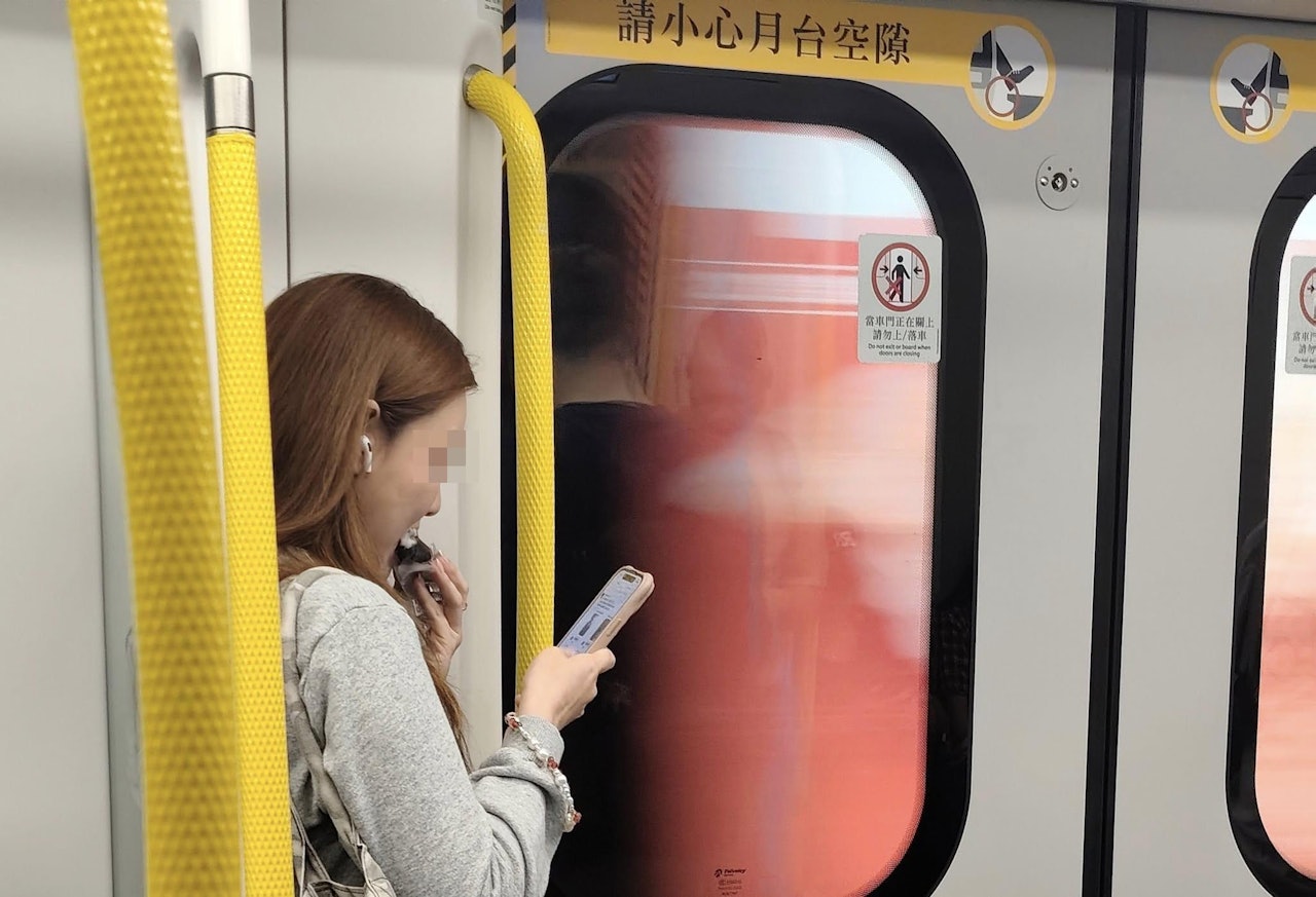 該港女邊吃飯團邊看手機,相當專心。(Facebook群組「車cam L(香港群組)」影片截圖)