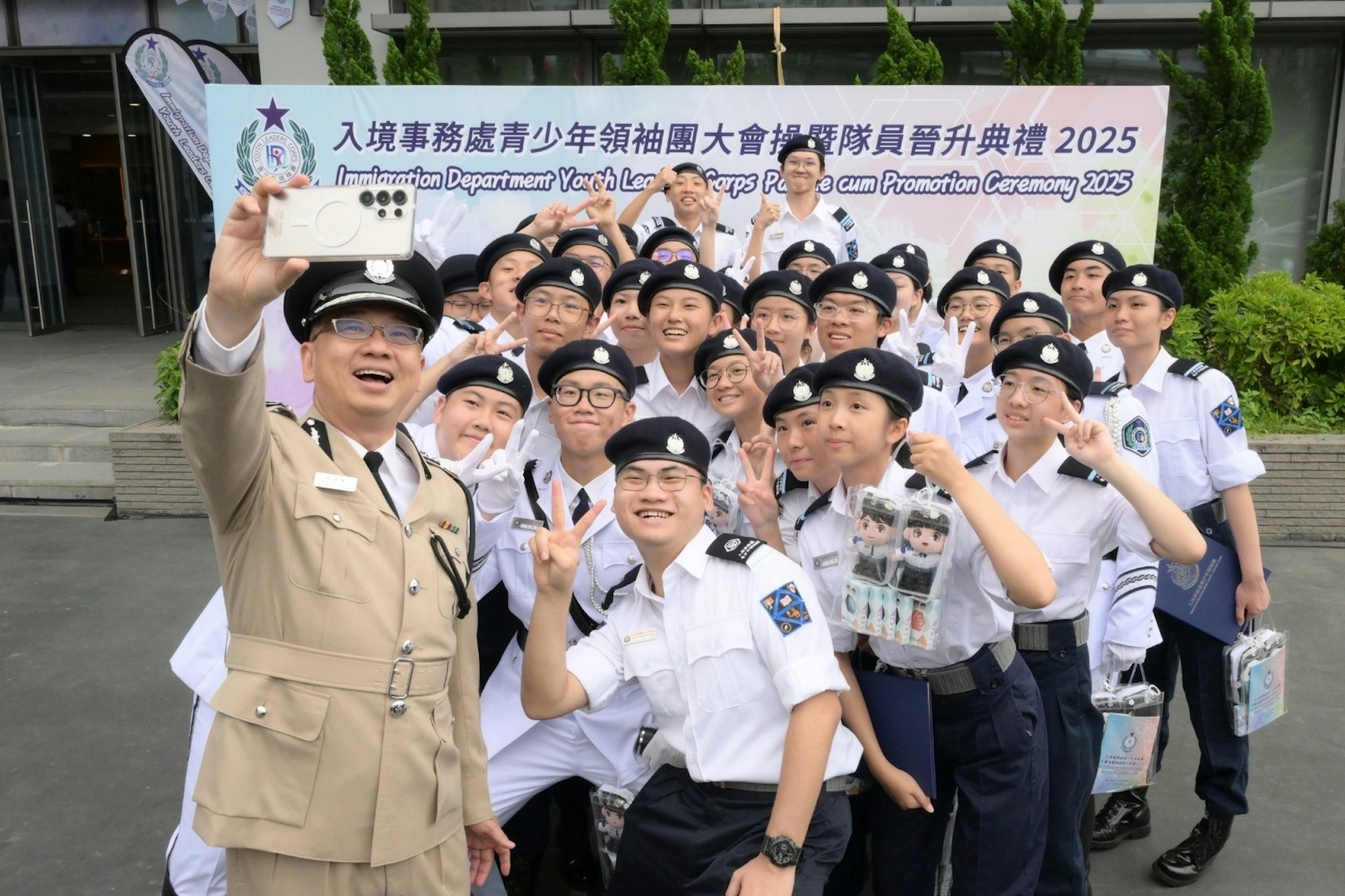 2025年5月25日,入境事務處青少年領袖團大會操暨隊員晉升典禮2025舉行。圖為入境處處長郭俊峯(左一)和參與會操的隊員自拍留念。(政府新聞處圖片) 2025年5月25日,入境事務處青少年領袖團大會操暨隊員晉升典禮2025舉行。圖為入境處處長郭俊峯(左一)和參與會操的隊員自拍留念。(政府新聞處圖片)