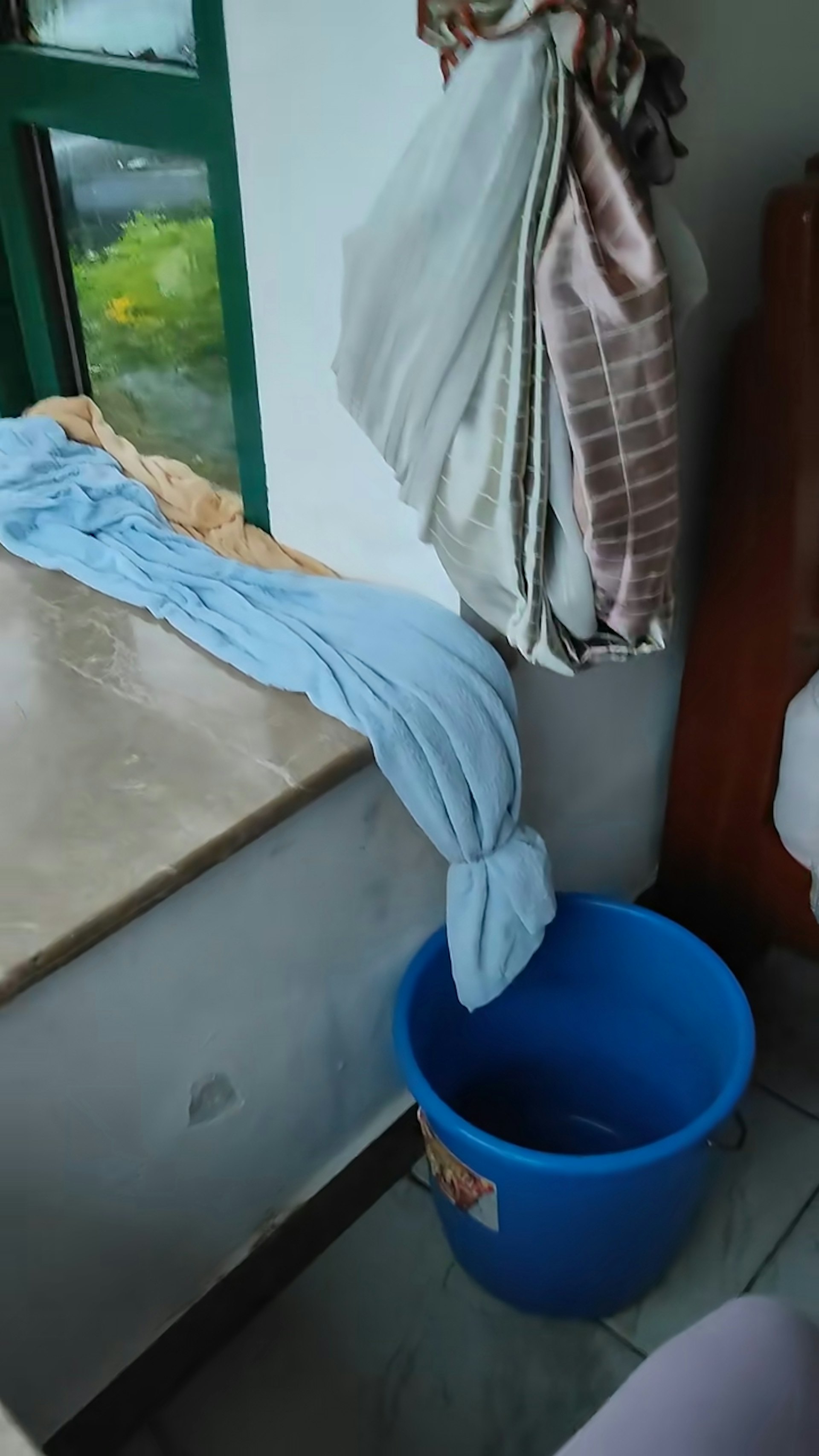 把毛巾塞在窗邊,然後將毛巾的一邊懸在窗台,下面放一個水桶,毛巾吸滿水後便會滴進水桶內。(小紅書@大然然的咖啡角)