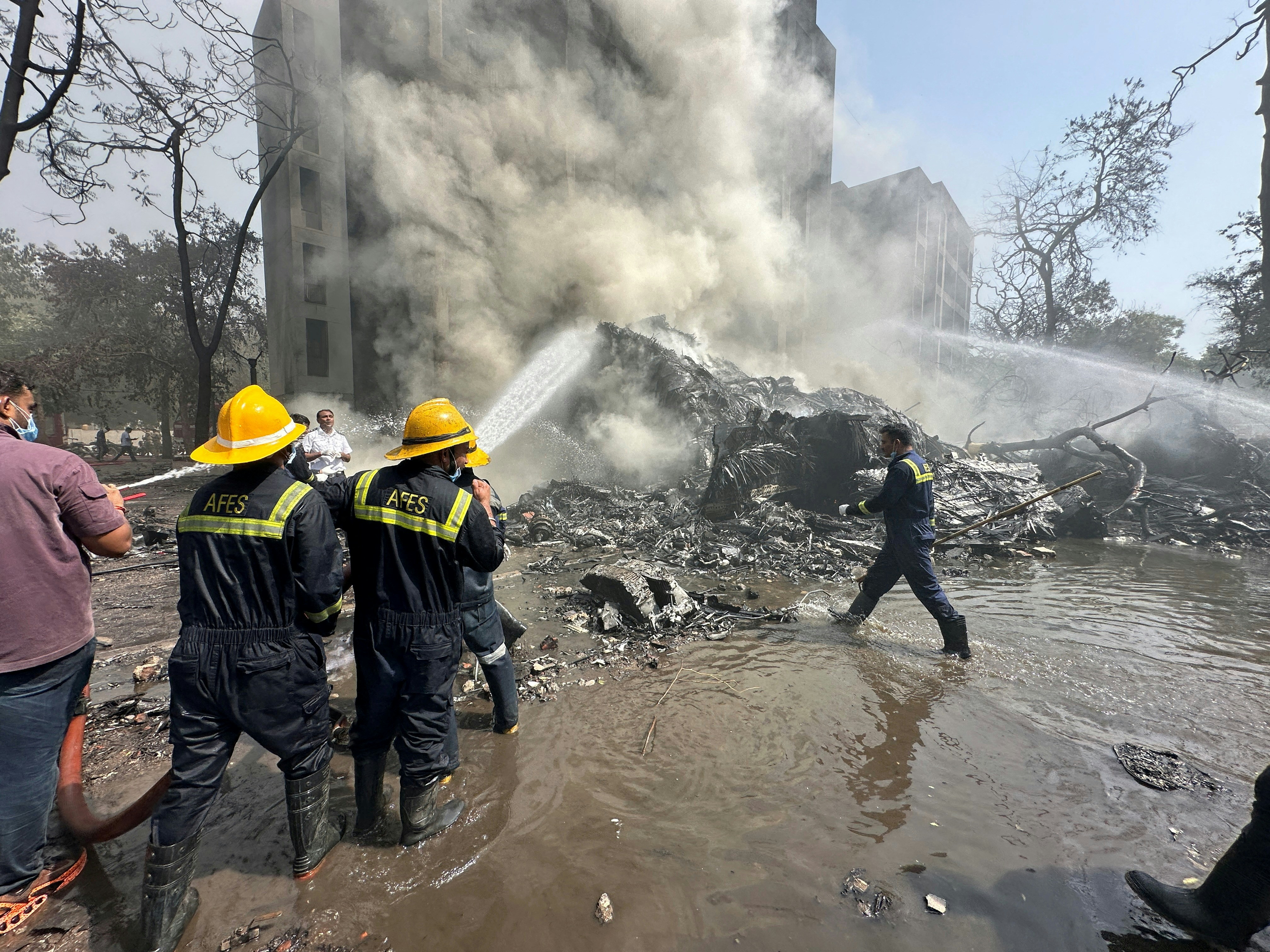 2025年6月12日,印度艾哈迈达巴德,印度航空客机坠毁现场浓烟滚滚,救援人员正在现场进行救援工作。(Reuters)