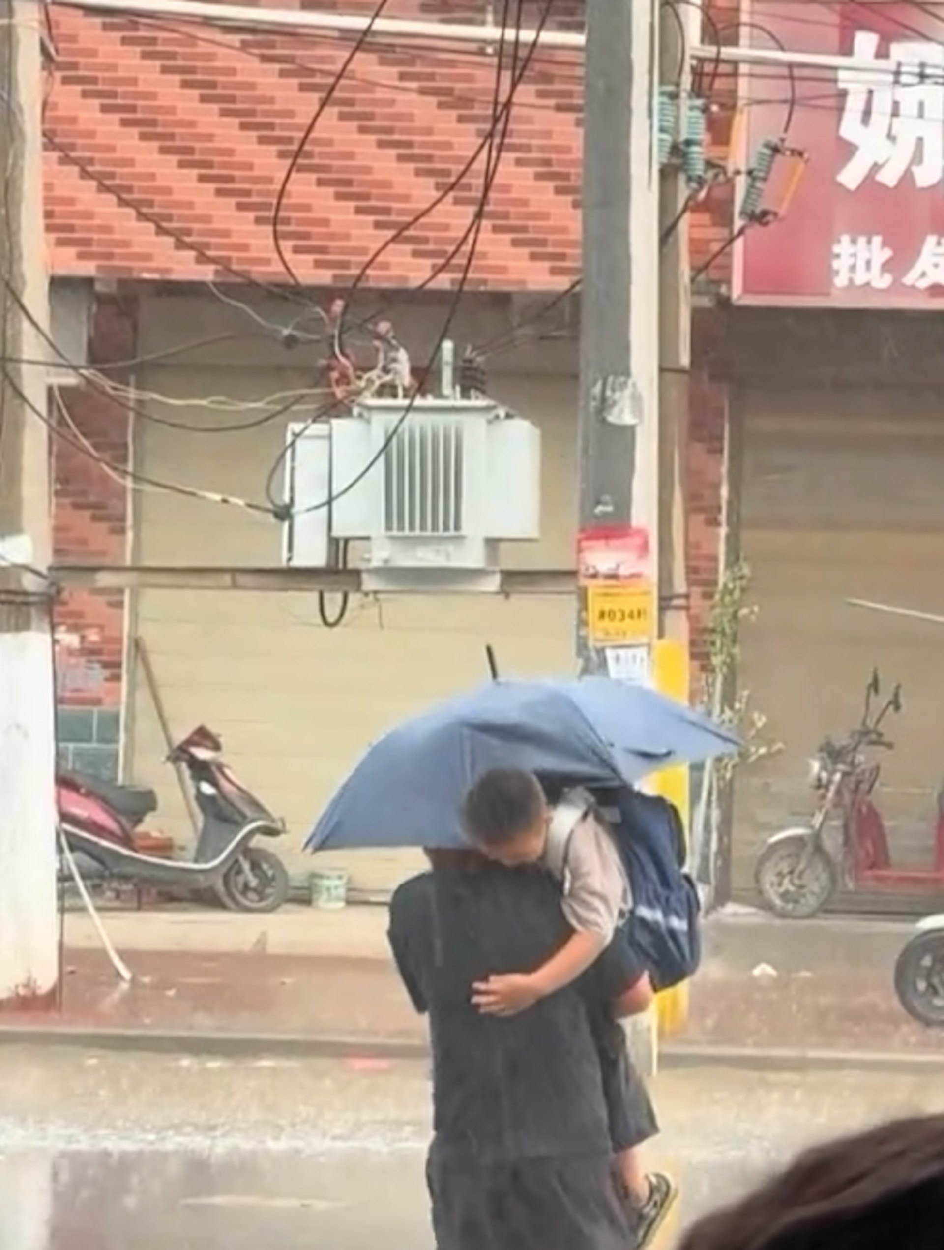 父親大雨天撐傘抱子場面感人。(影片截圖) 父親大雨天撐傘抱子場面感人。(影片截圖)